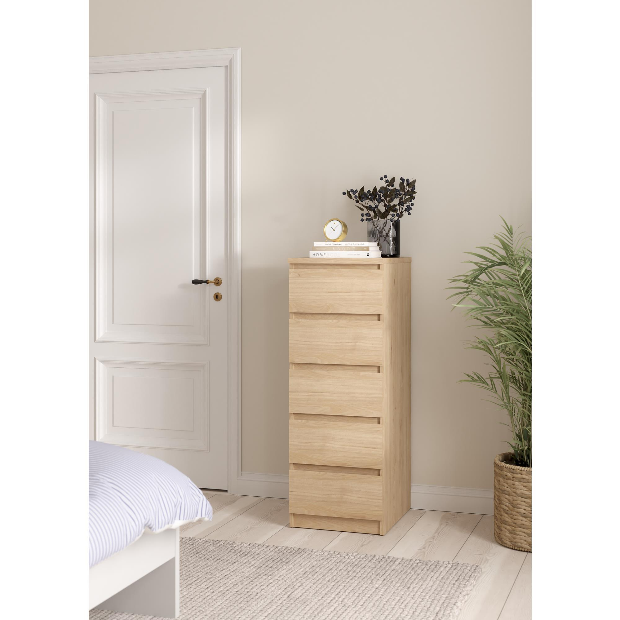 Un mueble de cajones de madera clara junto a una puerta blanca.