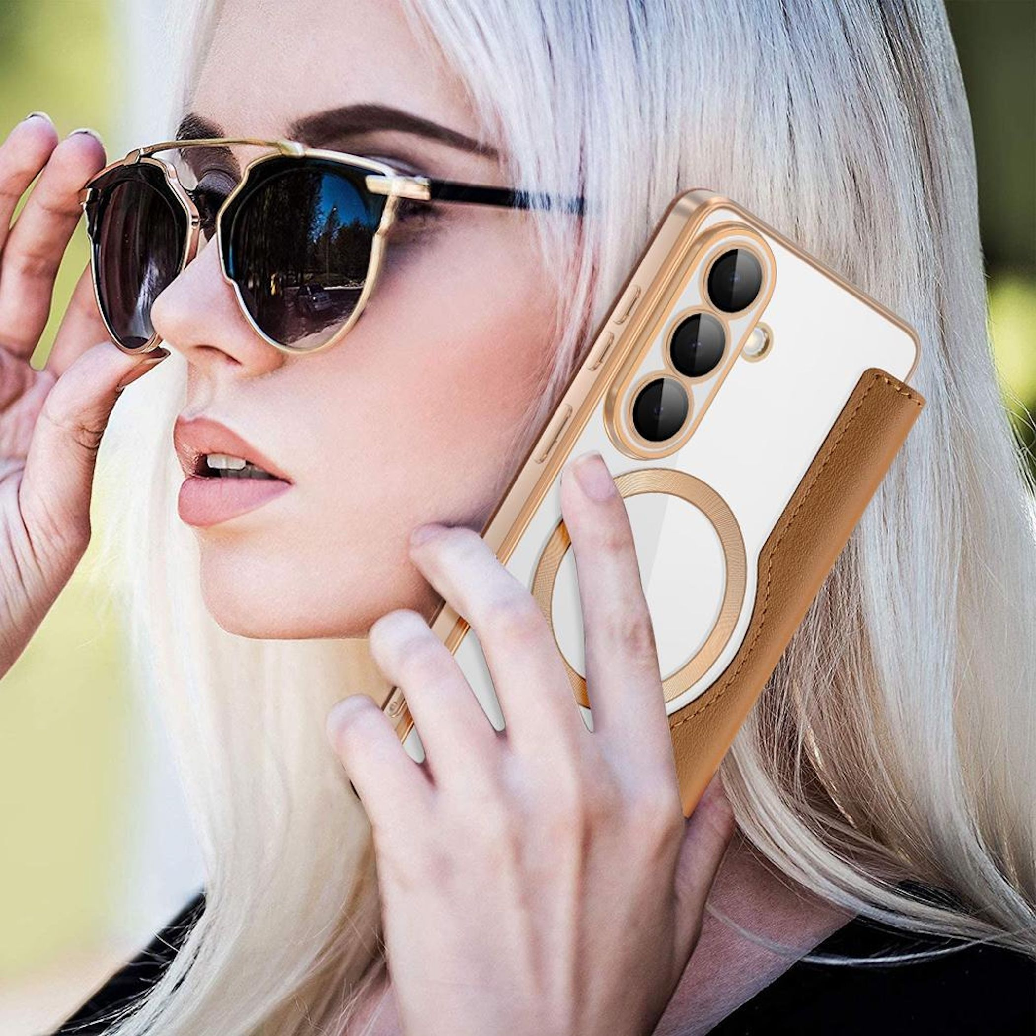 Frau mit blonden Haaren und Sonnenbrille hält ein Handy mit braunem Lederetui.