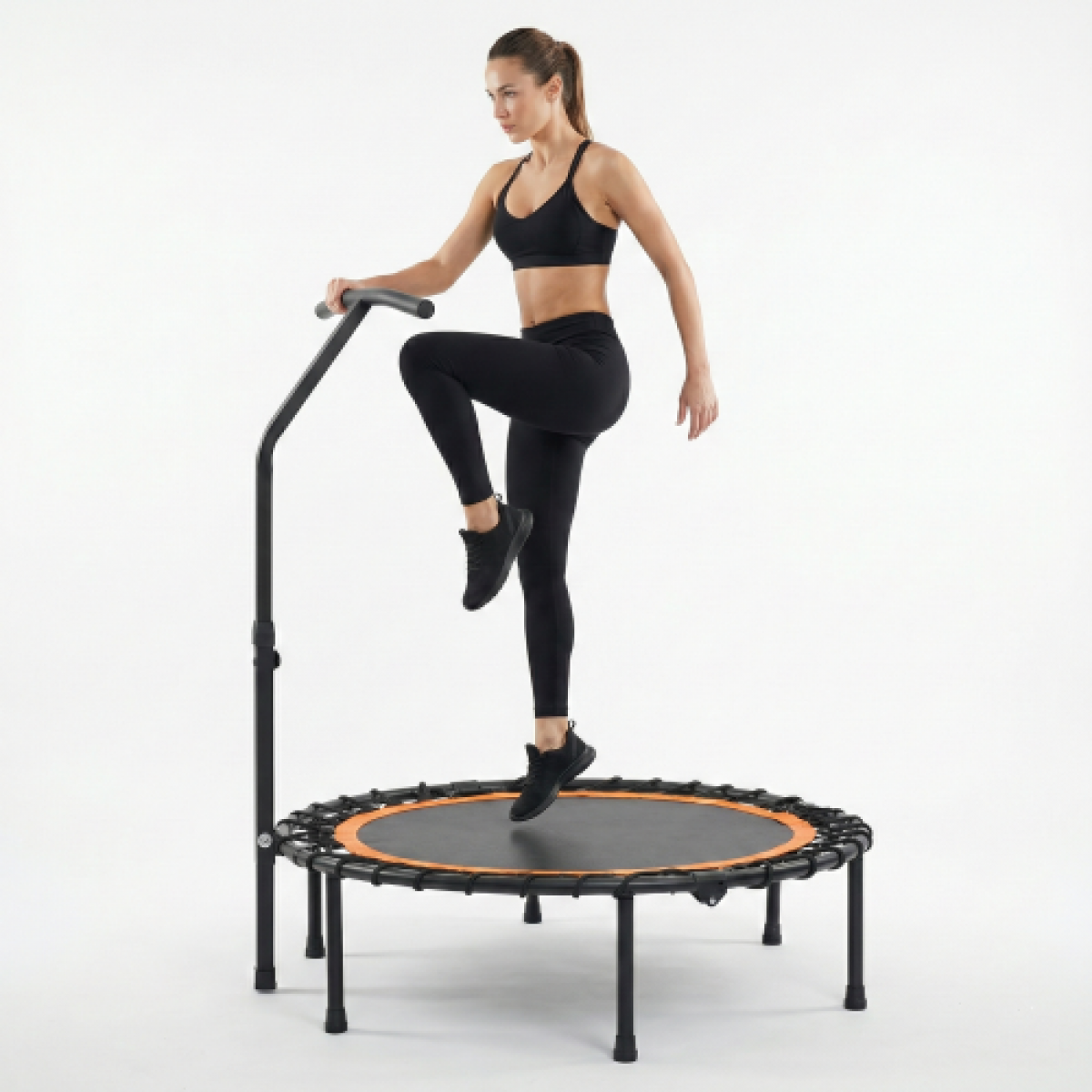 Frau in Schwarz übt auf einem Trampolin mit Griff.