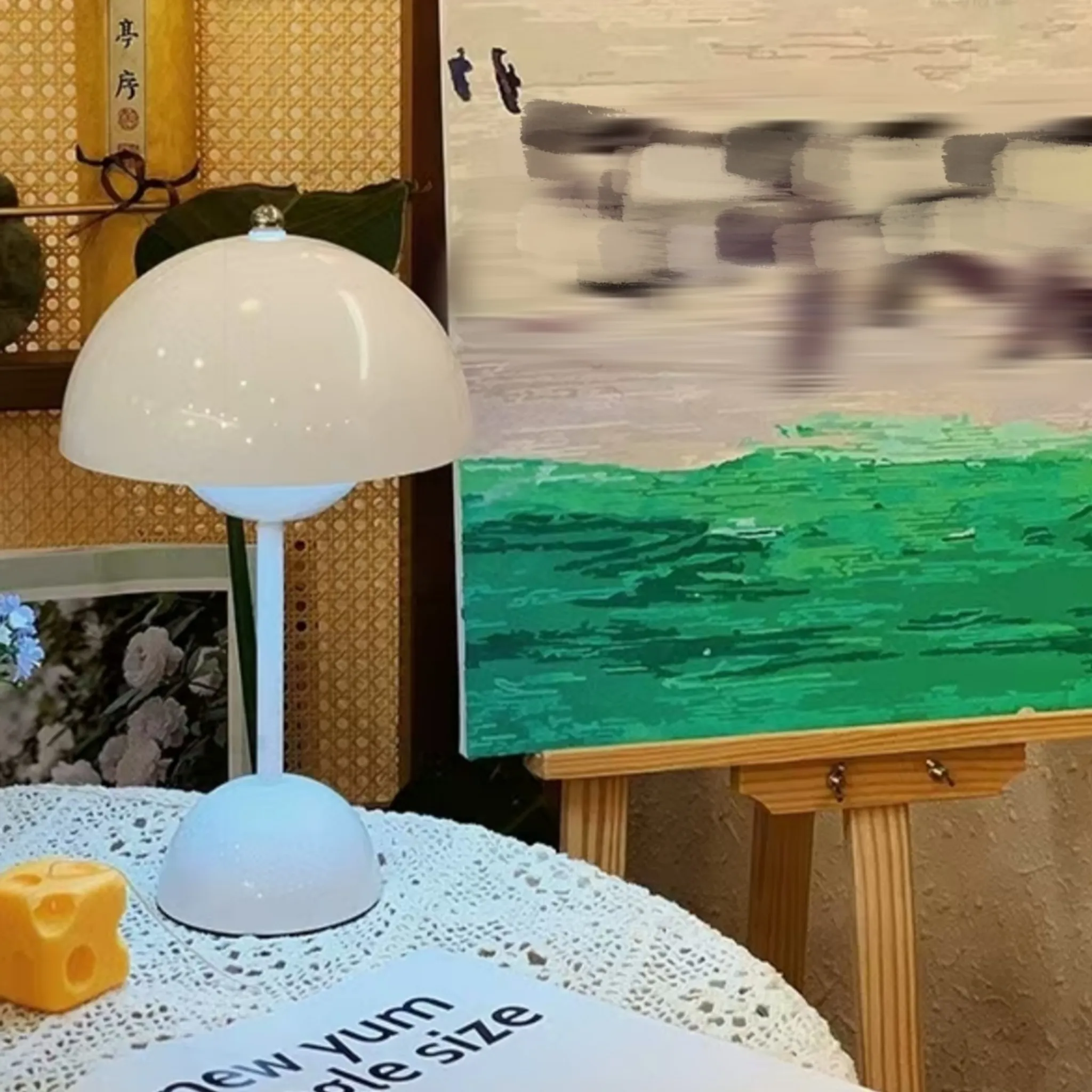 Eine weiße Pilzlampe steht auf einem Tisch mit einer Decke.