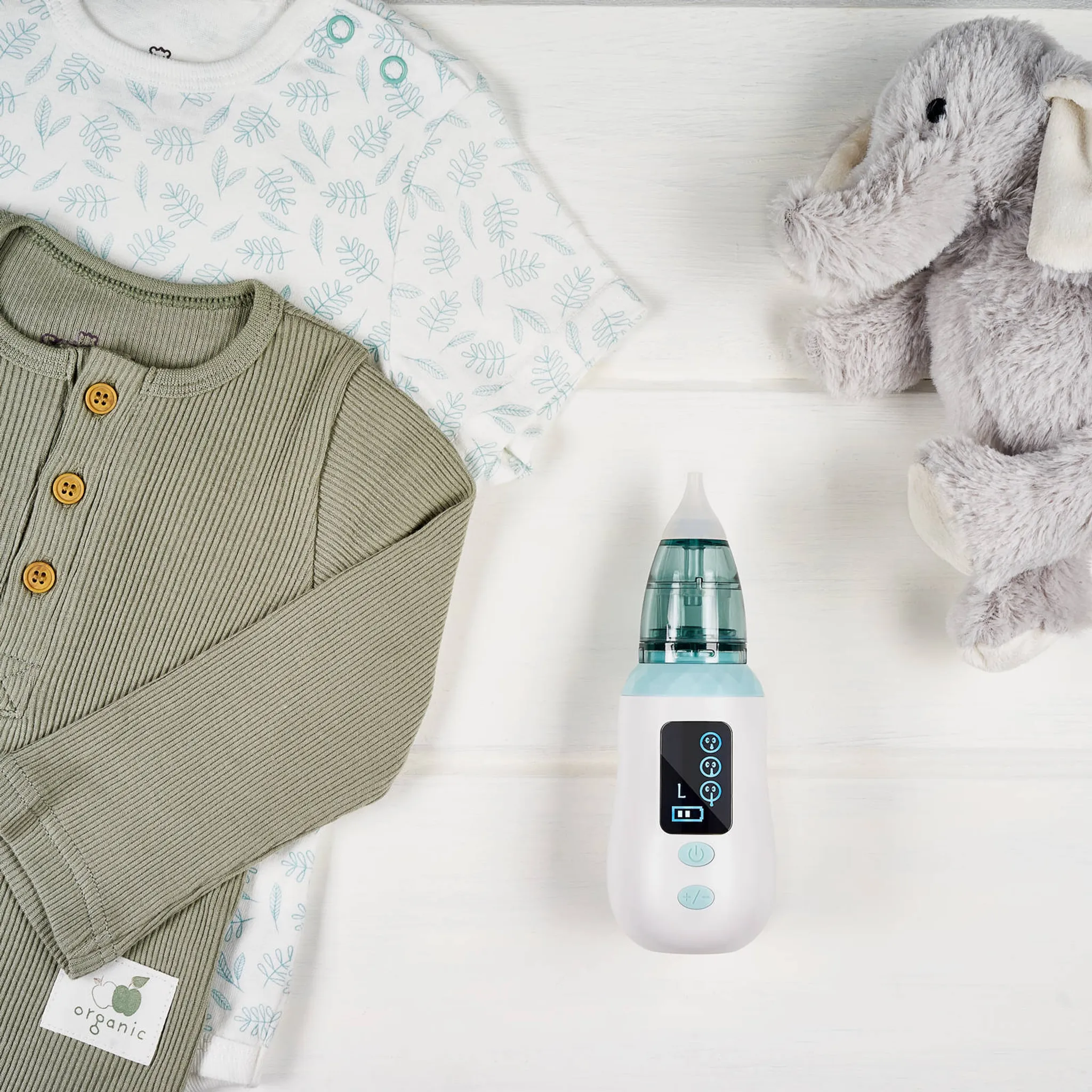 Babykleidung, ein Elefantenspielzeug und ein Nasensauger auf weißem Hintergrund.