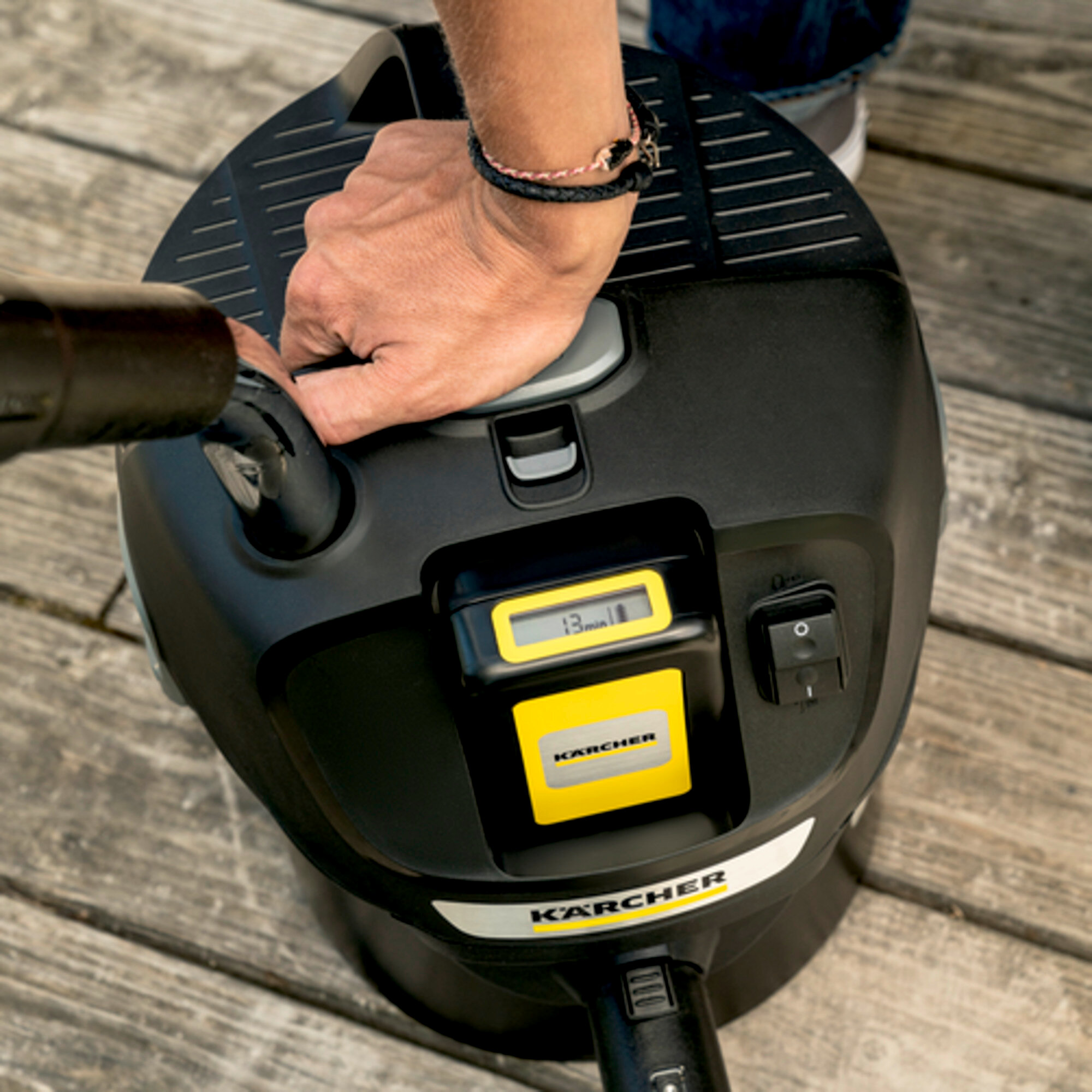 Main actionne nettoyeur Karcher noir avec écran et interrupteur.