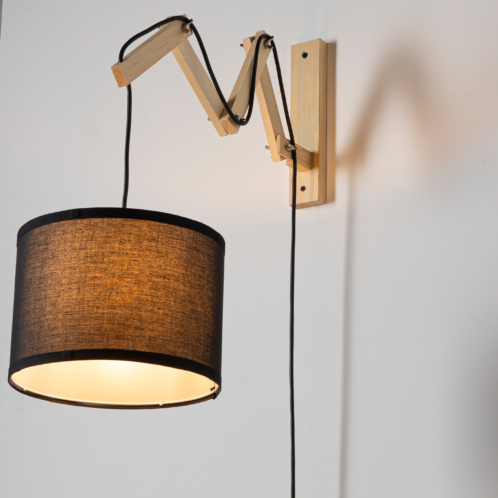 Lámpara de pared de madera con pantalla de tela negra y brazo articulado.