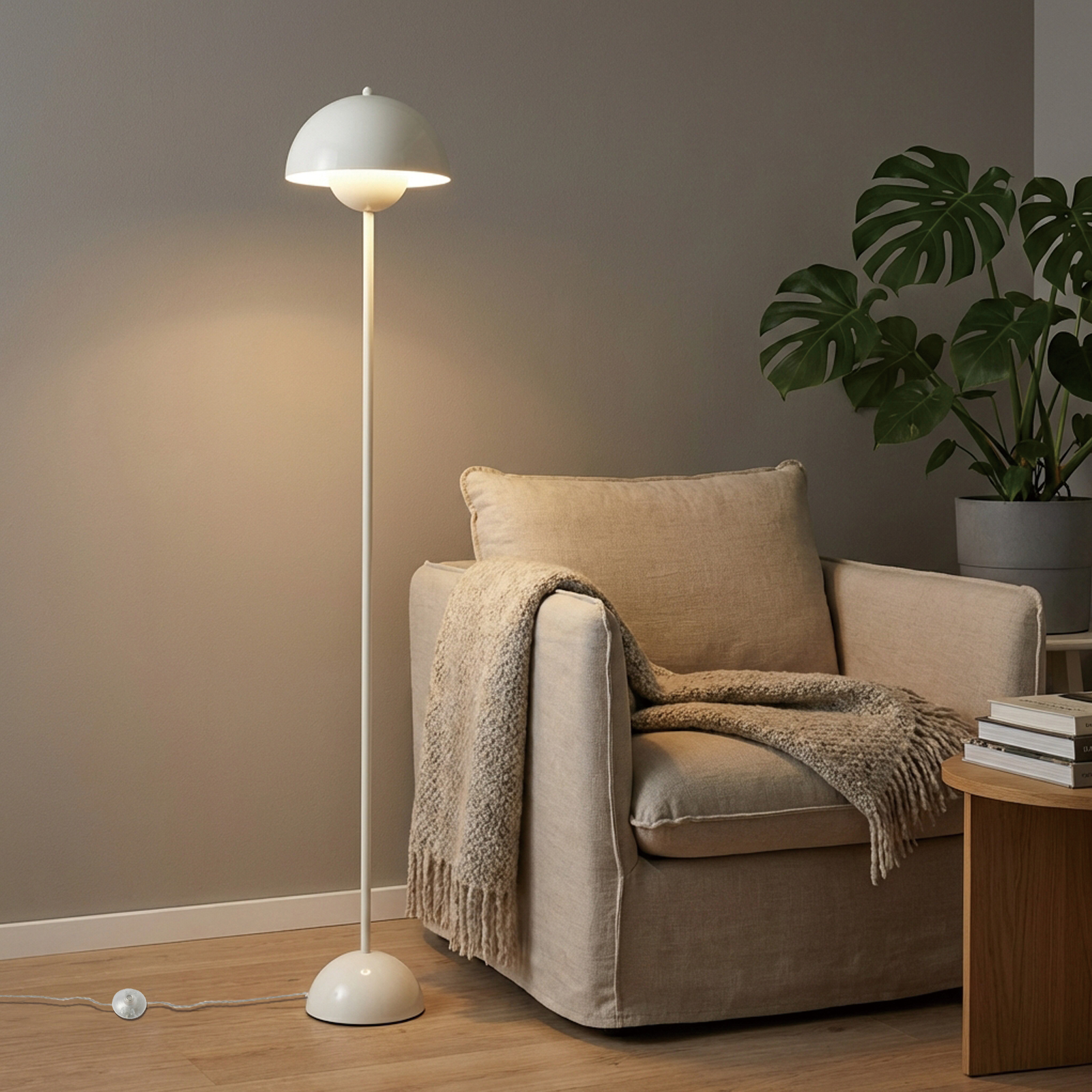 Una lámpara de pie blanca ilumina junto a un sillón beige con manta.