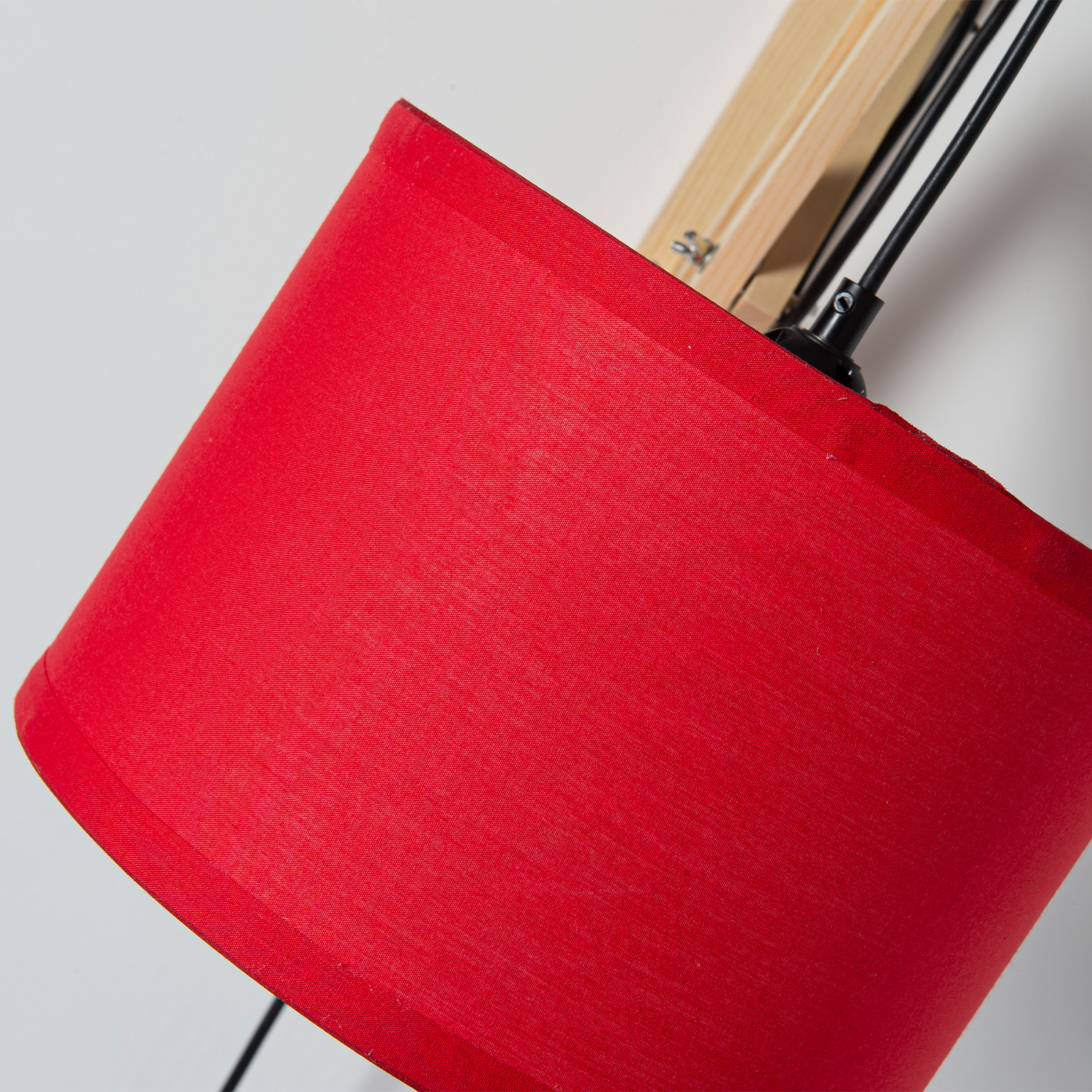 Pantalla de lámpara roja con brazo de madera y cables negros.