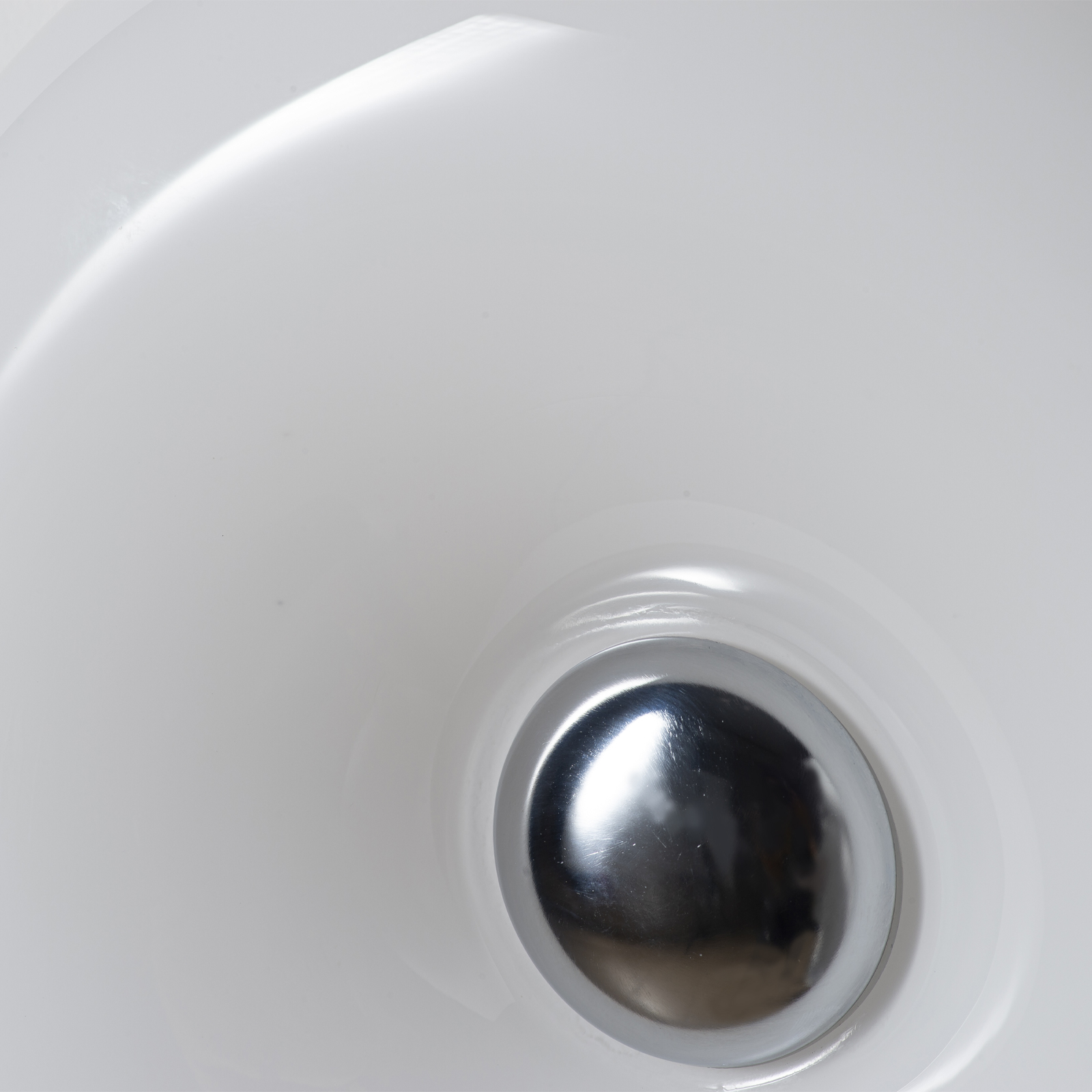 Un desagüe cromado brillante en un fregadero blanco.