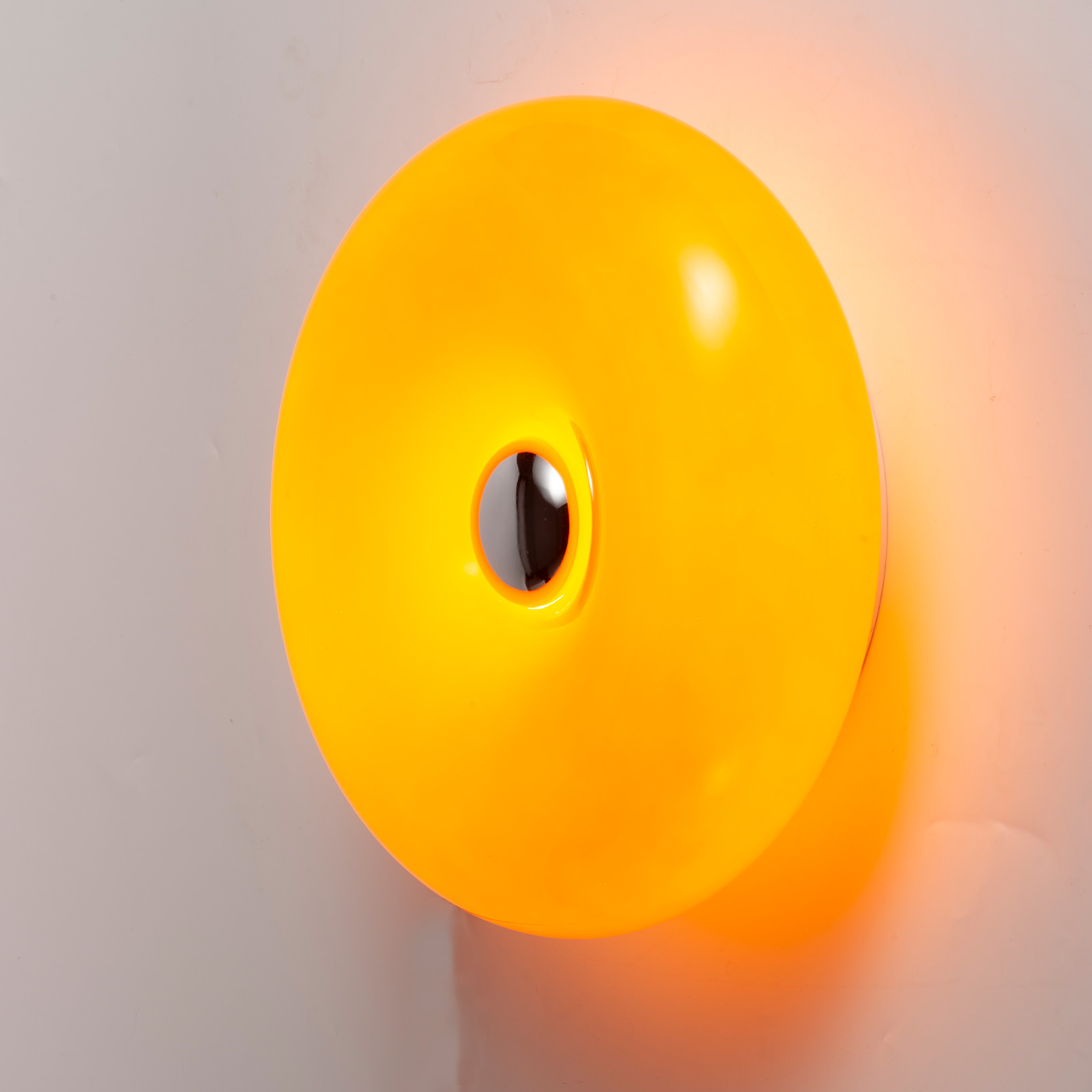 Una lámpara redonda, de color amarillo brillante, con un recorte central sobre fondo blanco.