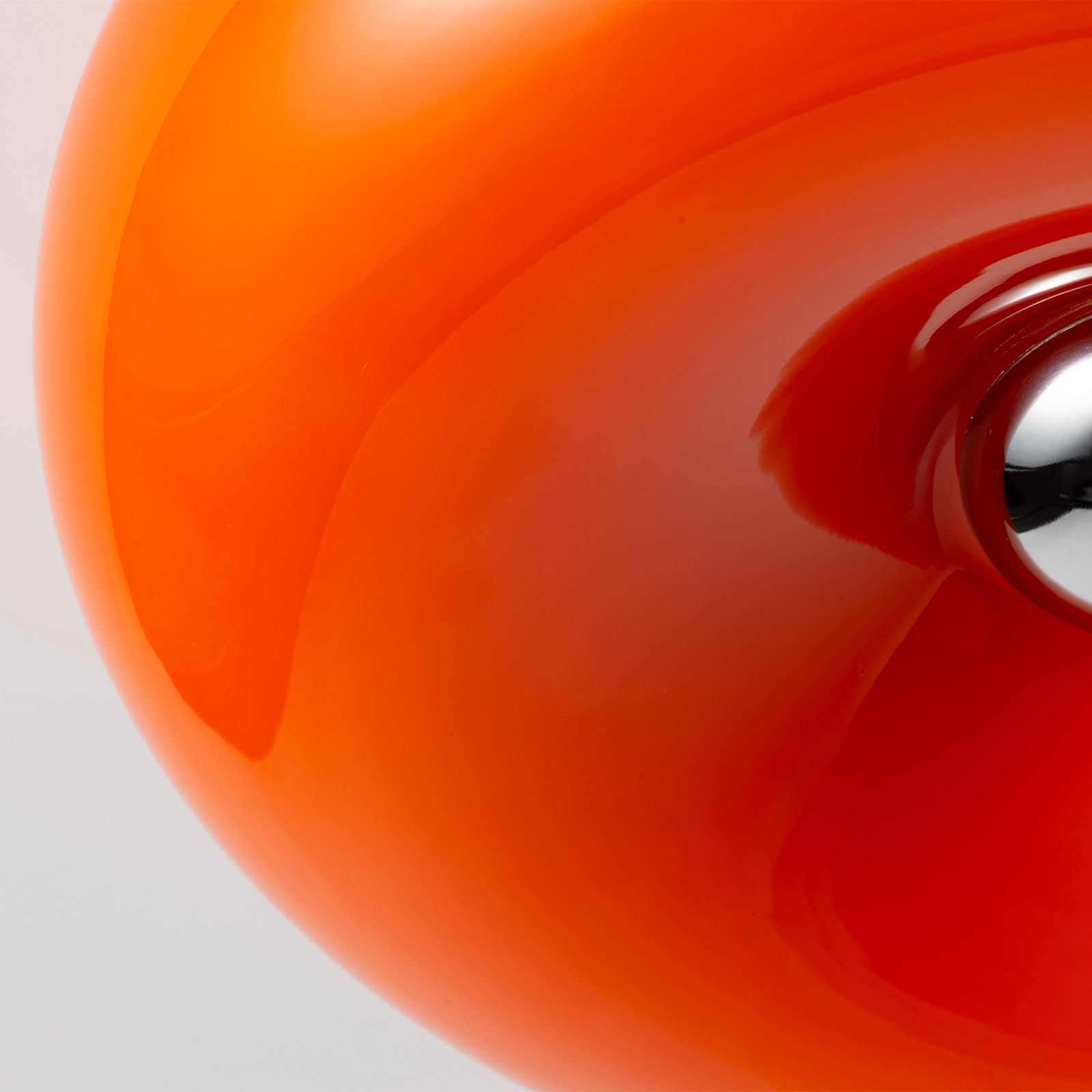 Primer plano de una esfera naranja brillante con un elemento metálico brillante.
