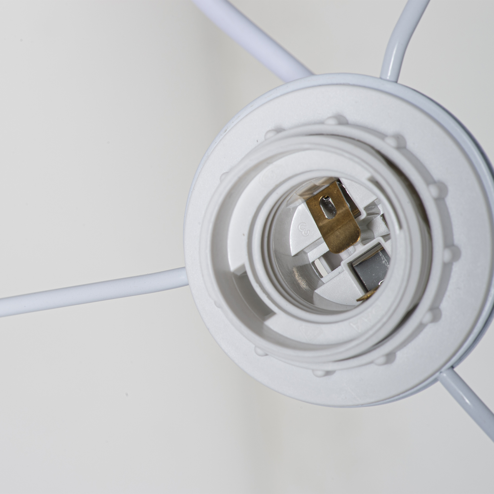 Primer plano de un portalámparas blanco con contactos metálicos y cables.