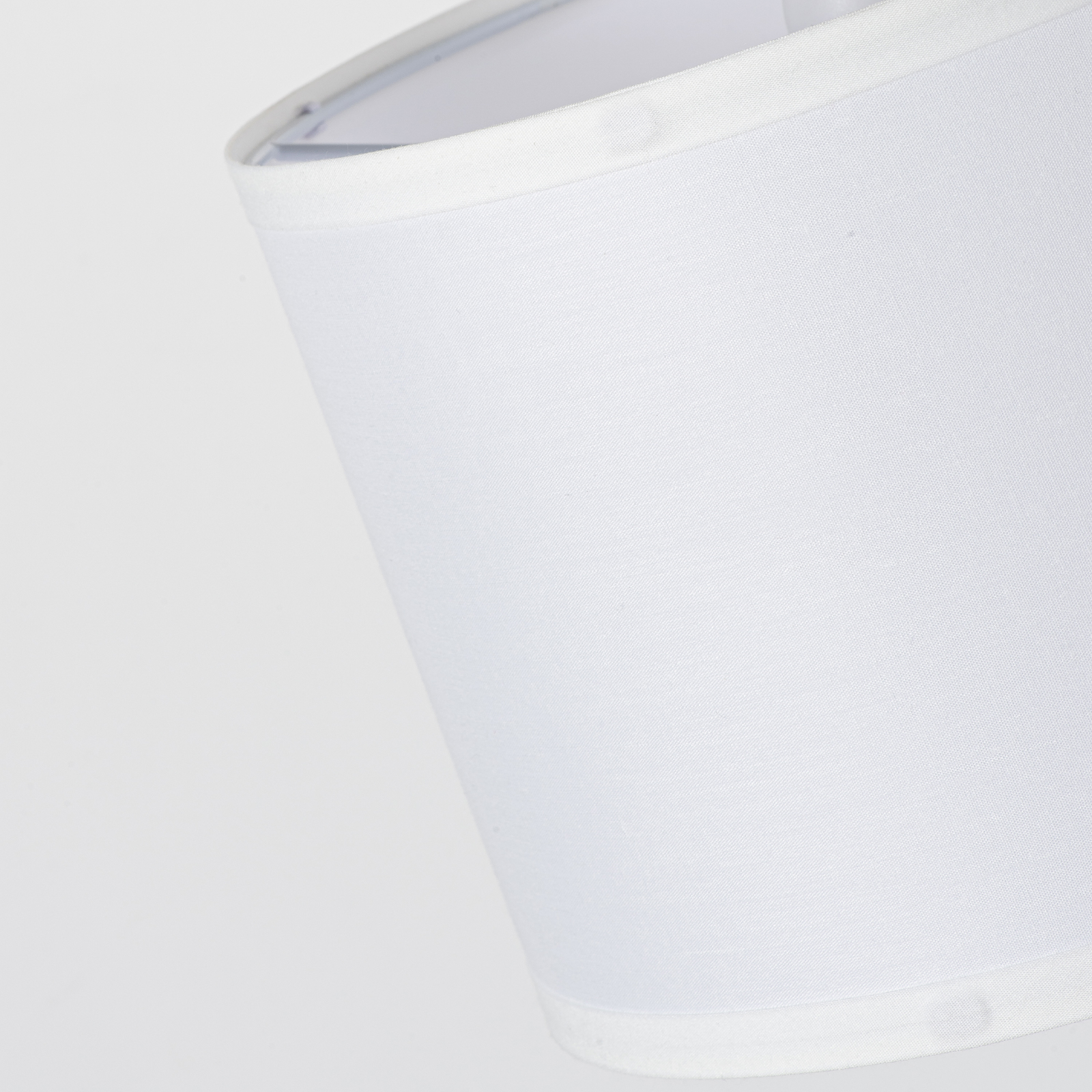 Primer plano de una pantalla de lámpara blanca con textura de tela sobre fondo blanco.