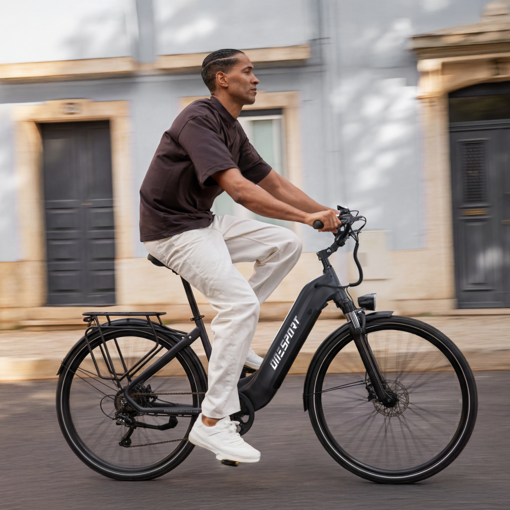 Uomo guida e-bike nera per strada, edifici sullo sfondo.
