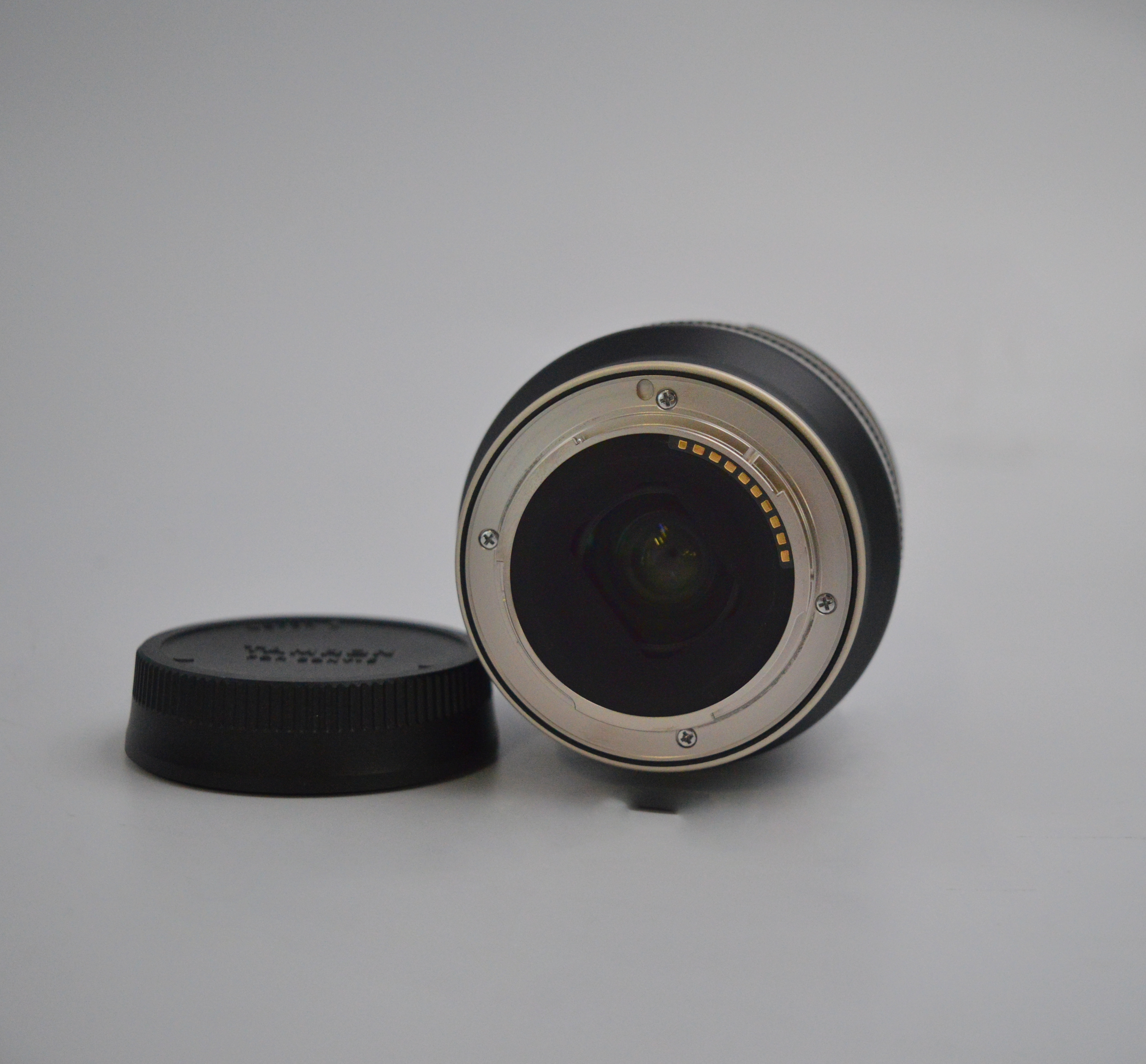 Tył obiektywu aparatu ze stykami i osobną osłoną.