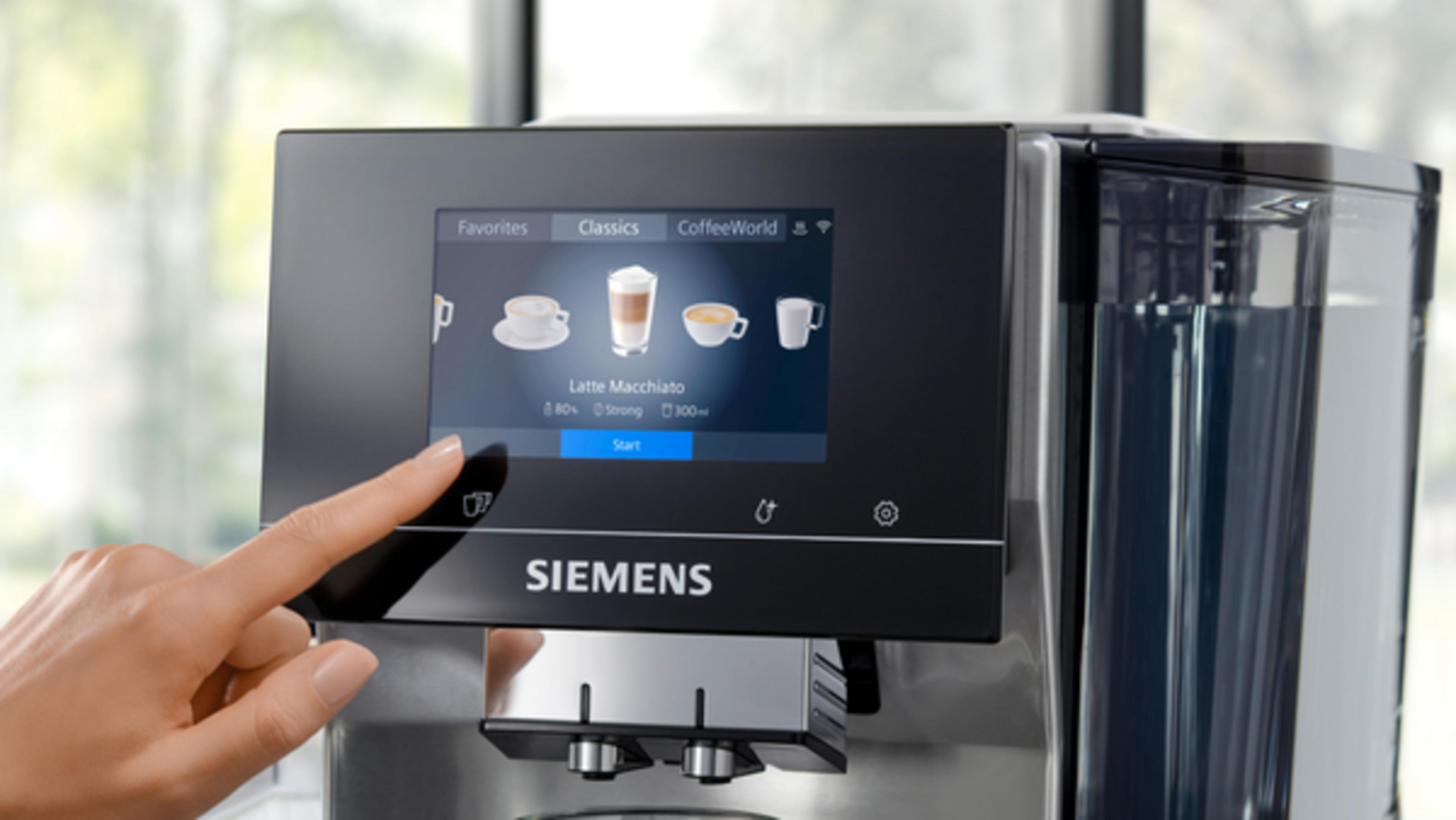 Bir parmak, Latte Macchiato seçeneklerini gösteren Siemens kahve makinesinin ekranına dokunuyor.