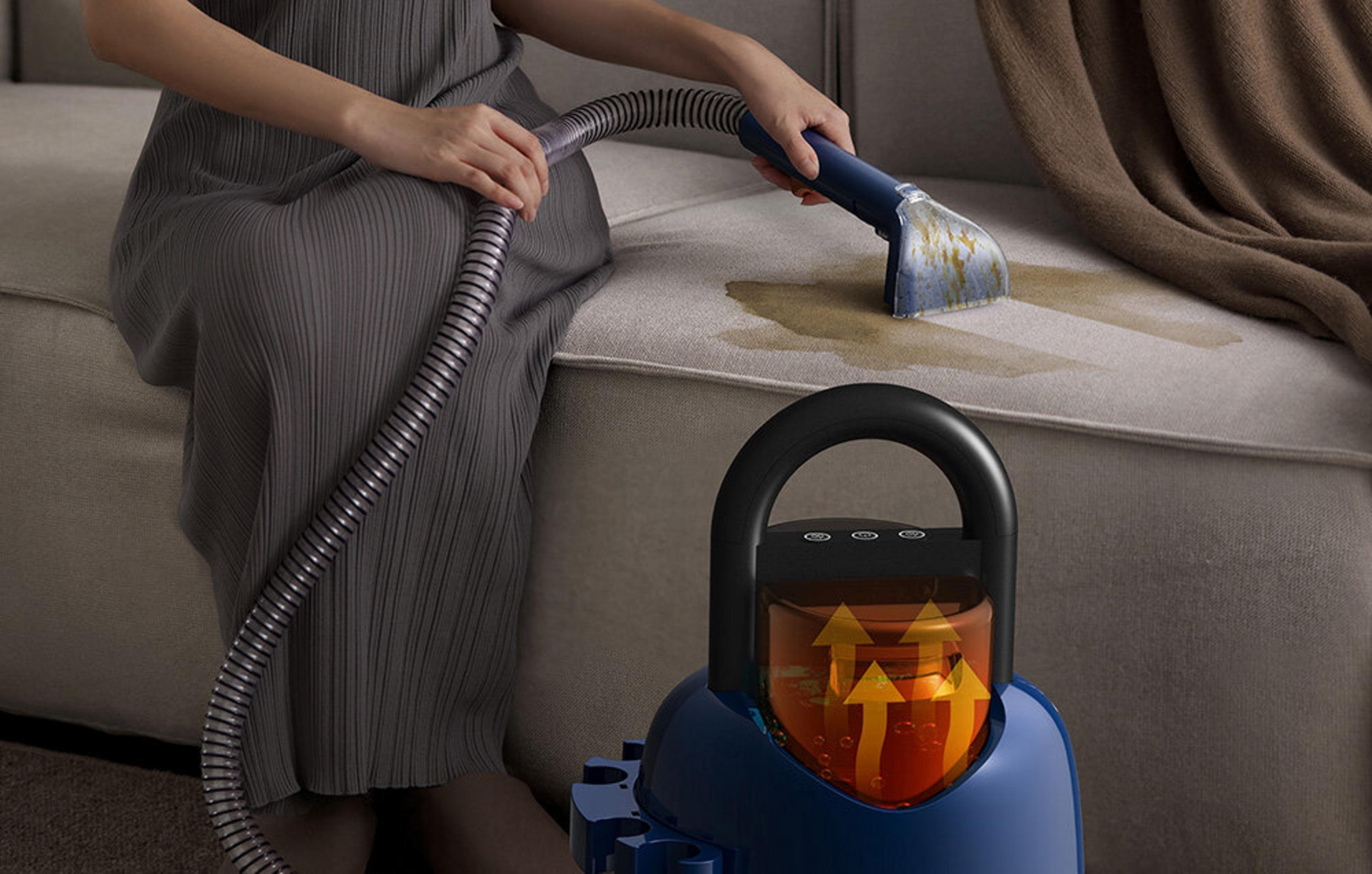 Una persona pulisce un divano con uno smacchiatore. Liquido giallo sul tessuto.