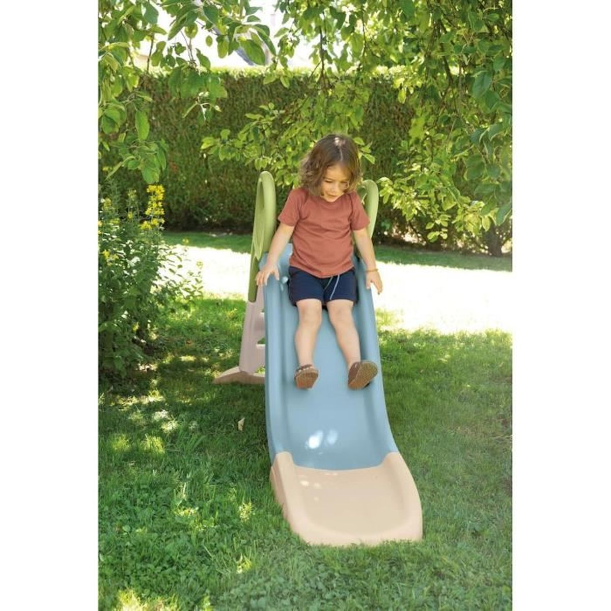 Un bambino scivola su uno scivolo blu in un giardino.