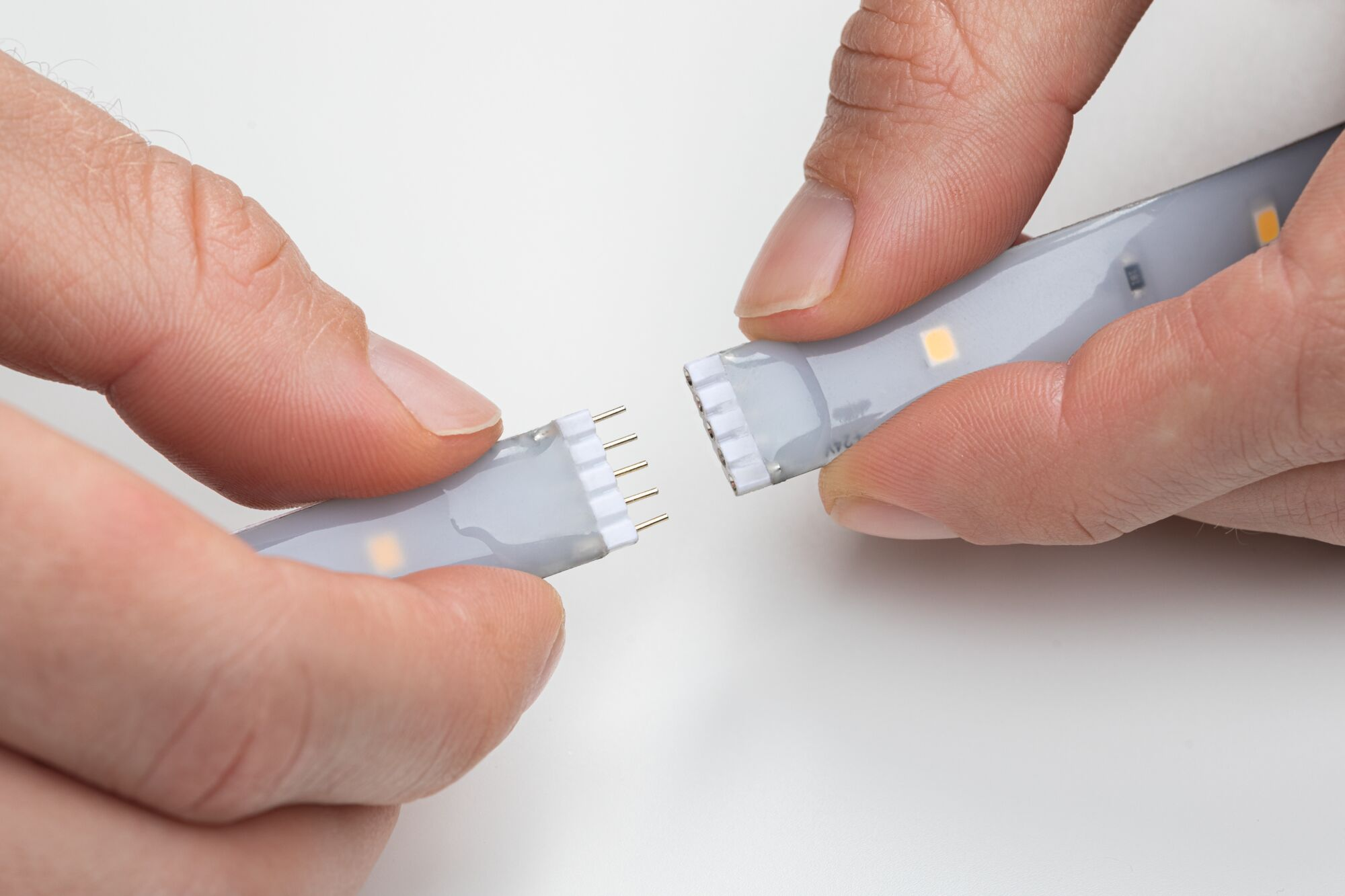 Hände verbinden LED-Streifen mit Pins. Nahaufnahme.