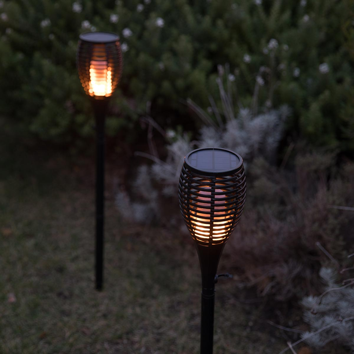 Zwei Solar-Gartenleuchten mit flackerndem Licht im Dunkeln.