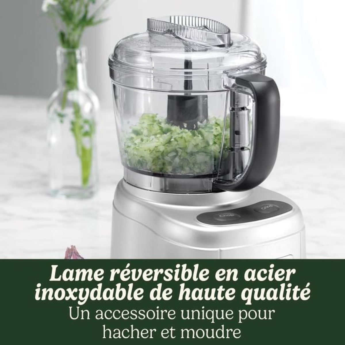 Robot da cucina argentato con verdure tritate e fiori sullo sfondo.