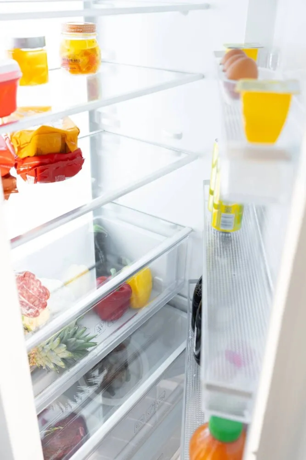 Un frigorifero aperto con cibo sugli scaffali.