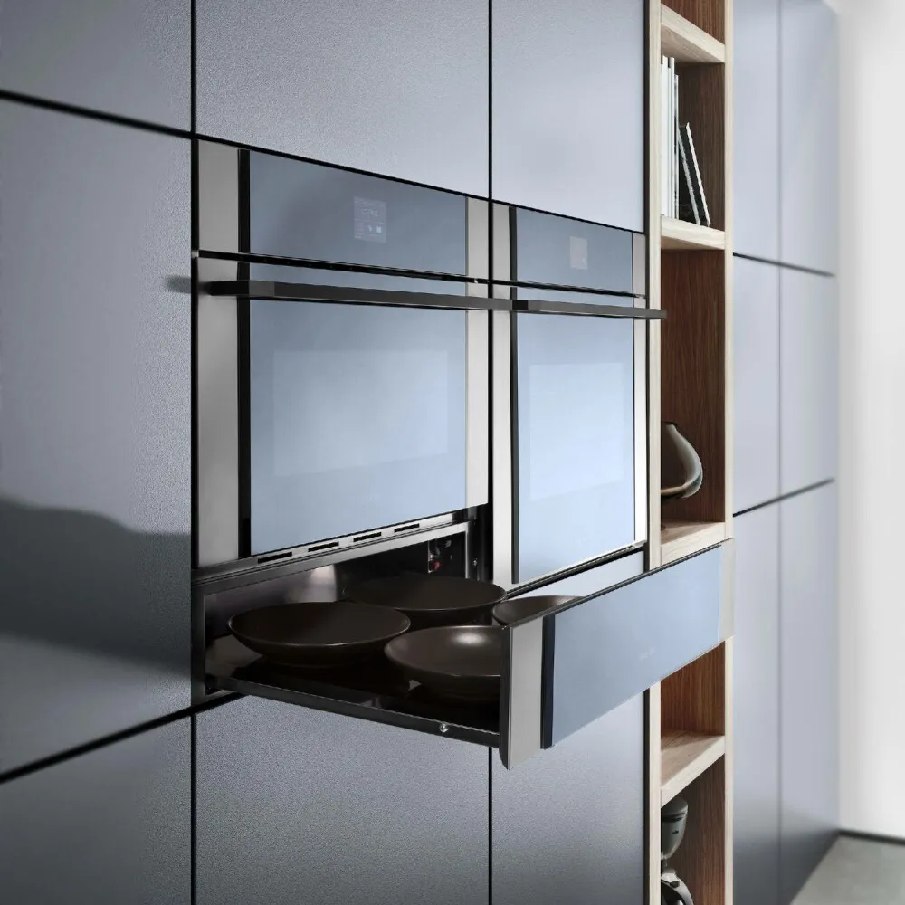 Cucina moderna con due forni da incasso e un cassetto estraibile con quattro piatti scuri.