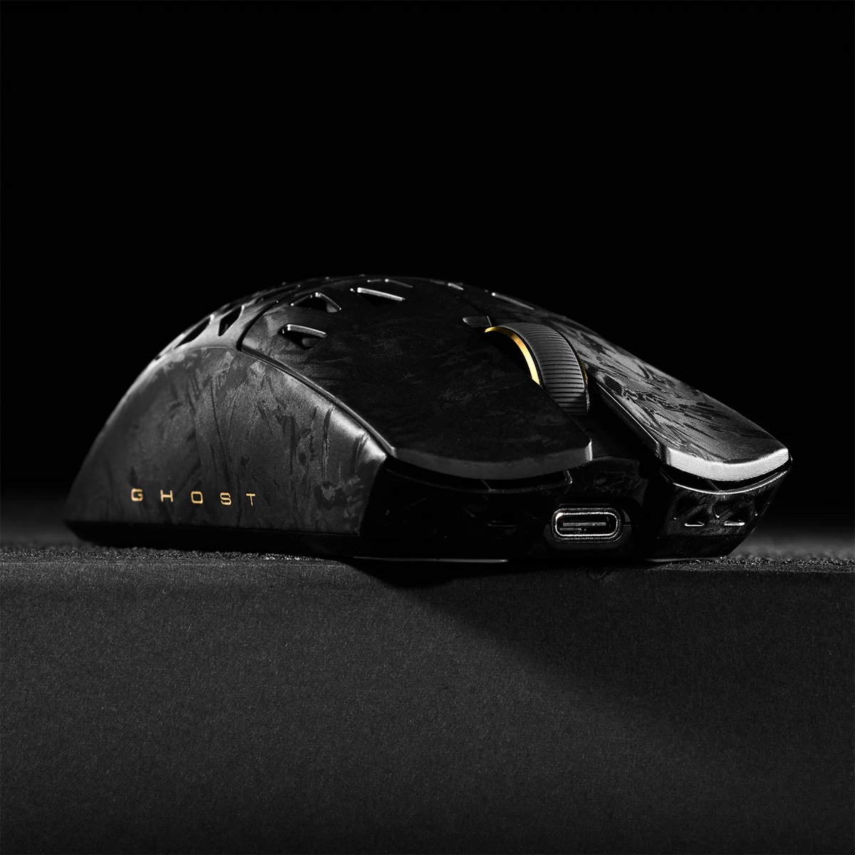 Zwarte gamingmuis met "GHOST" tekst en gouden scrollwiel.