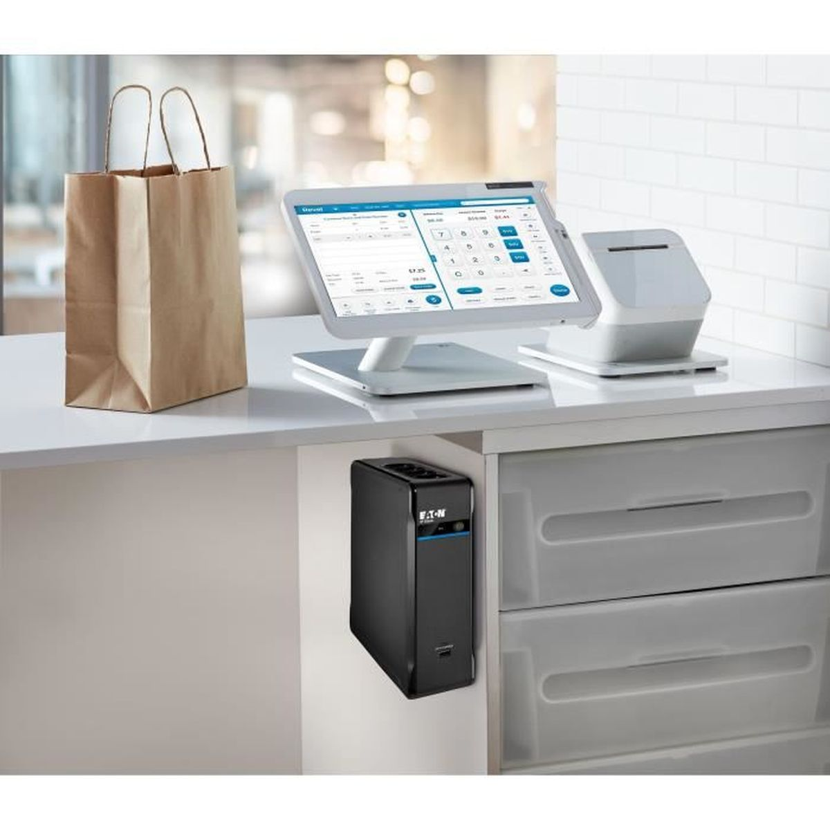 Kassensystem mit Tablet, Drucker, Einkaufstasche und USV auf einem Tresen.