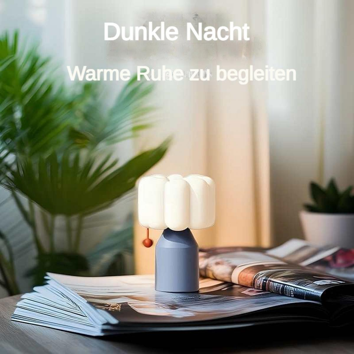 Kleine Lampe auf Magazinen mit Pflanzen im Hintergrund.