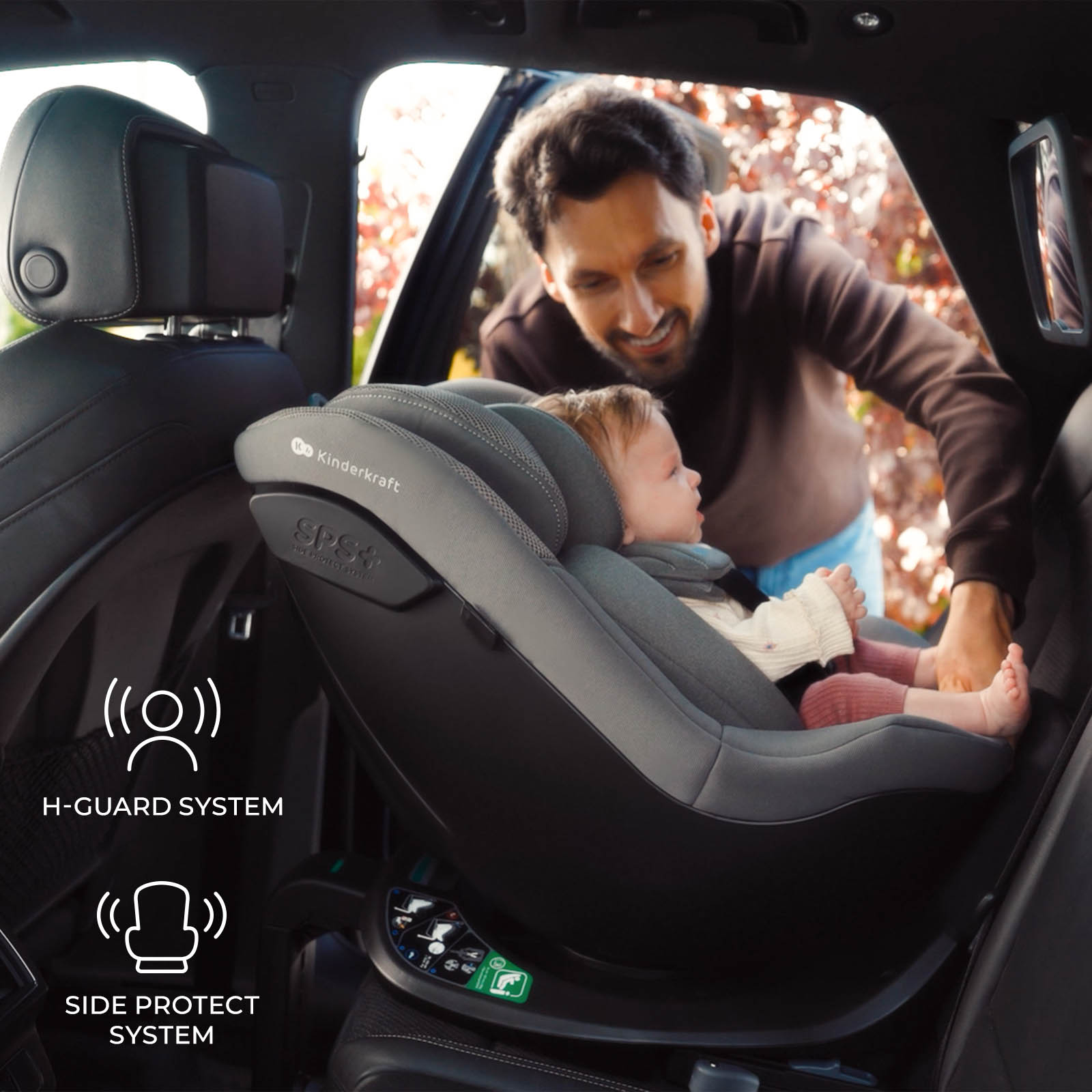 Vater beugt sich über ein Baby im Kindersitz im Auto.