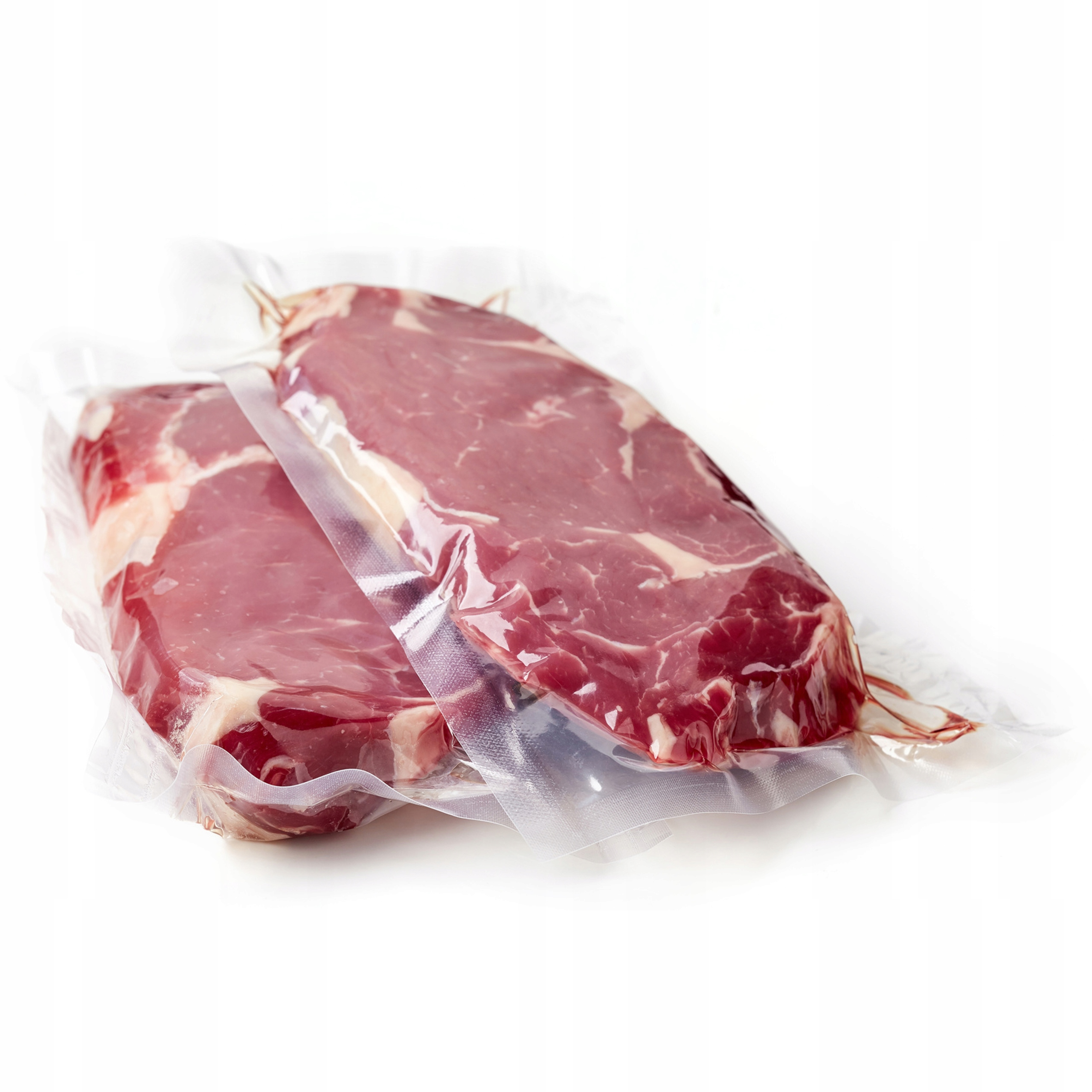 Dwa surowe steki wołowe pakowane próżniowo z przerostem tłuszczu.