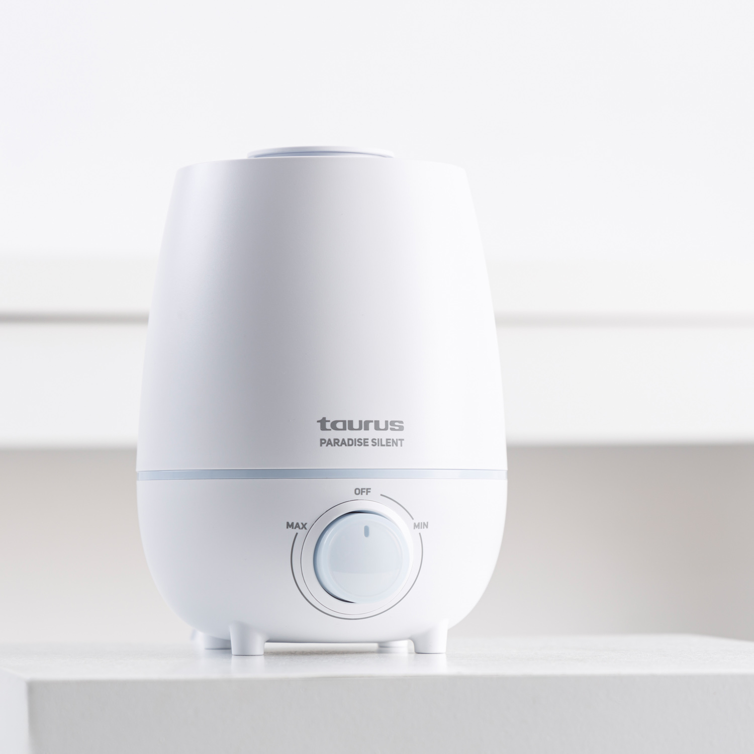 Un humidificador blanco con logo plateado y dial de control.