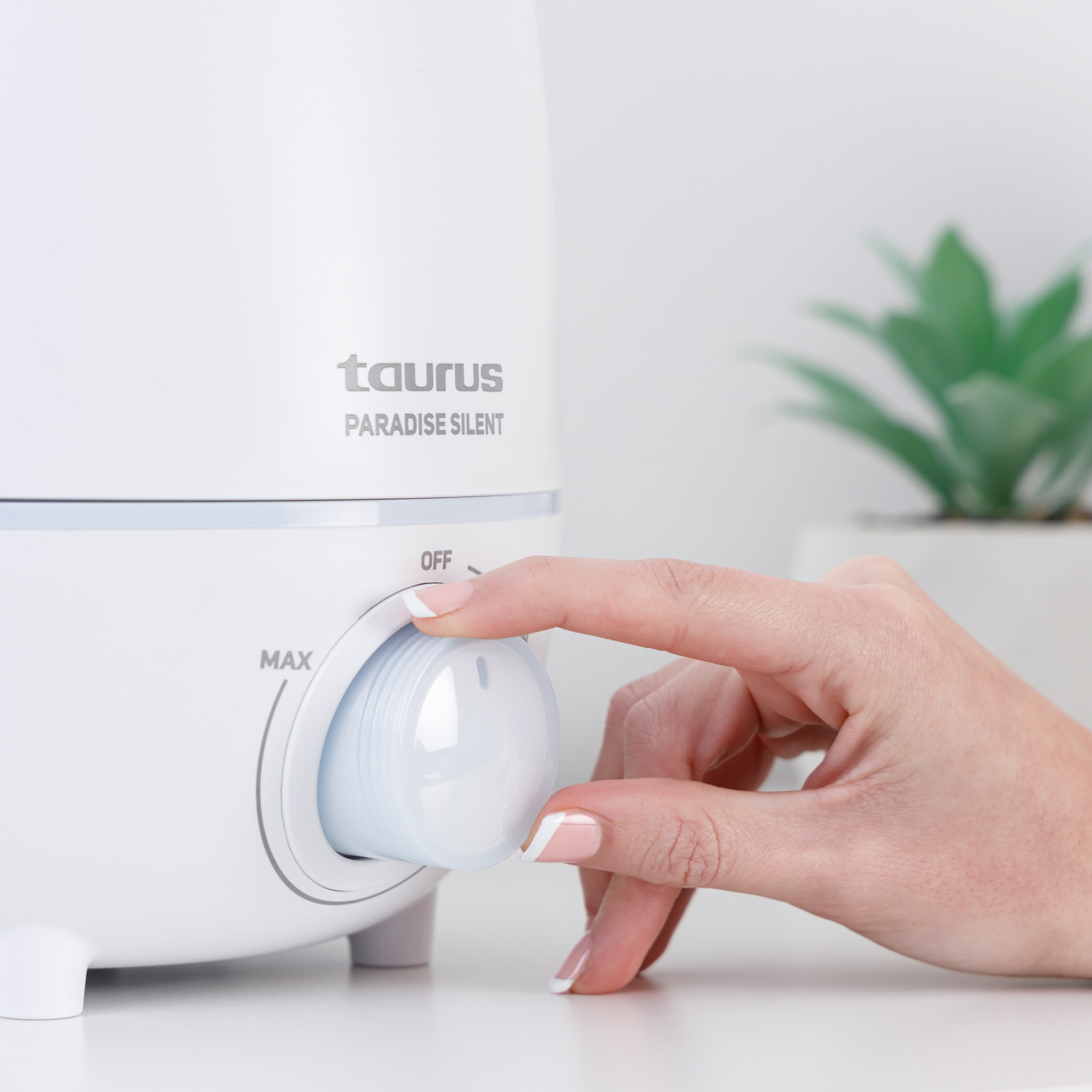 Una mano gira un dial en un humidificador blanco Taurus.