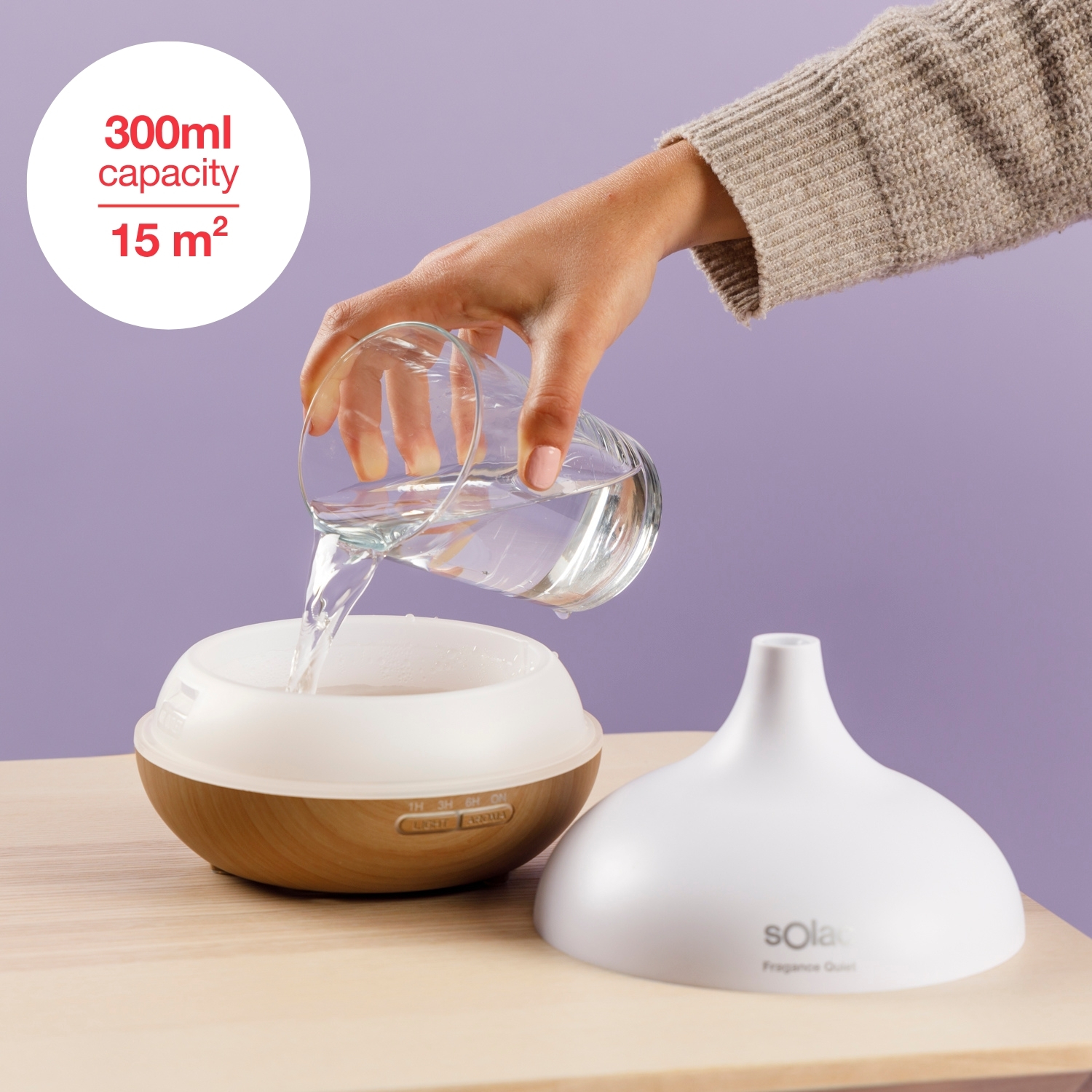 L'acqua viene versata in un diffusore di olio con base effetto legno su un tavolo.
