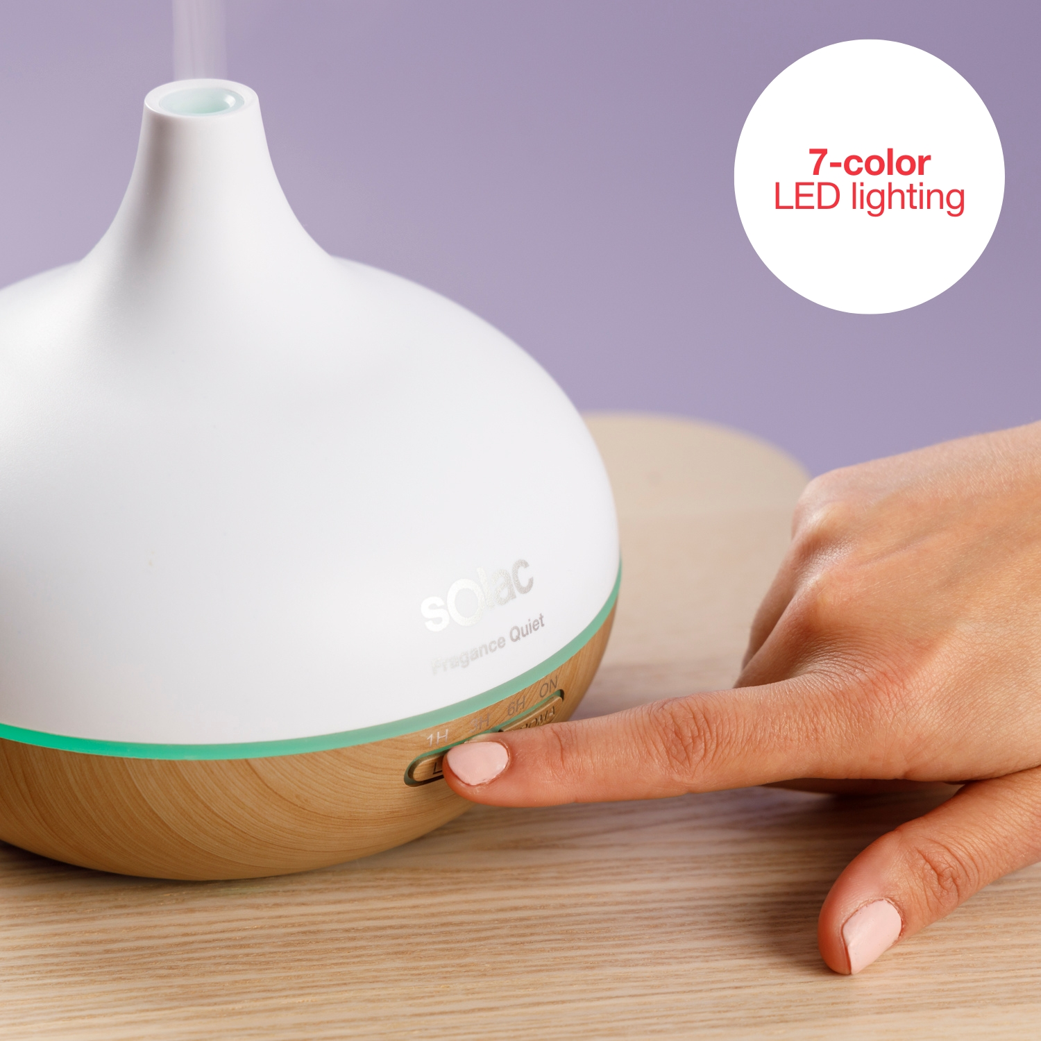 Una mano preme un pulsante su un diffusore bianco con base in legno.