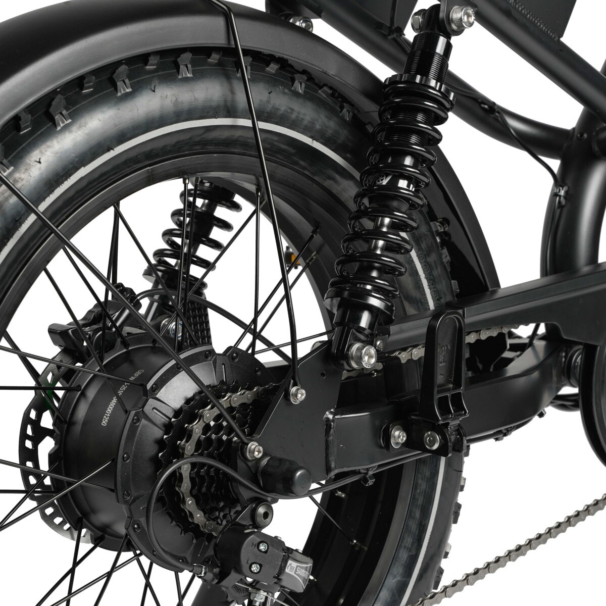 Zbliżenie czarnego tylnego koła roweru elektrycznego z amortyzatorem i łańcuchem.