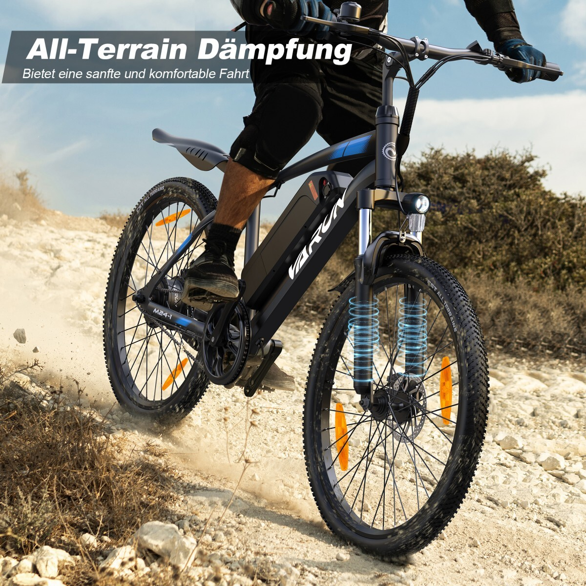 Osoba jedzie czarnym rowerem elektrycznym po kamienistej drodze. Podkreślono amortyzację.