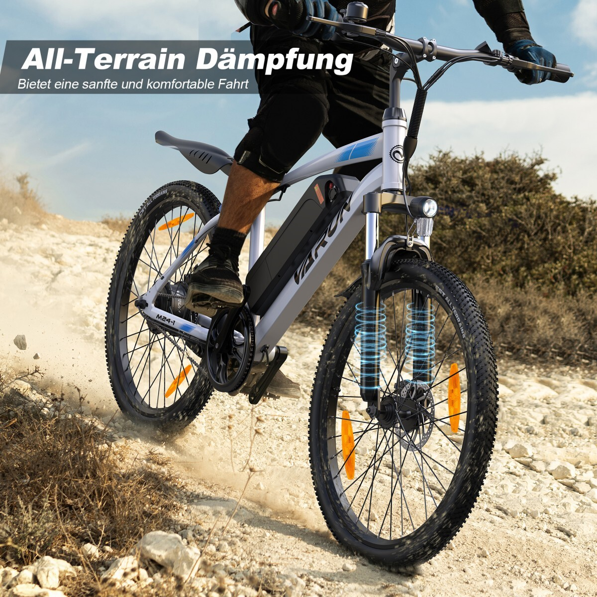 Mężczyzna jedzie rowerem elektrycznym po szutrowej ścieżce, podkreślając amortyzację.