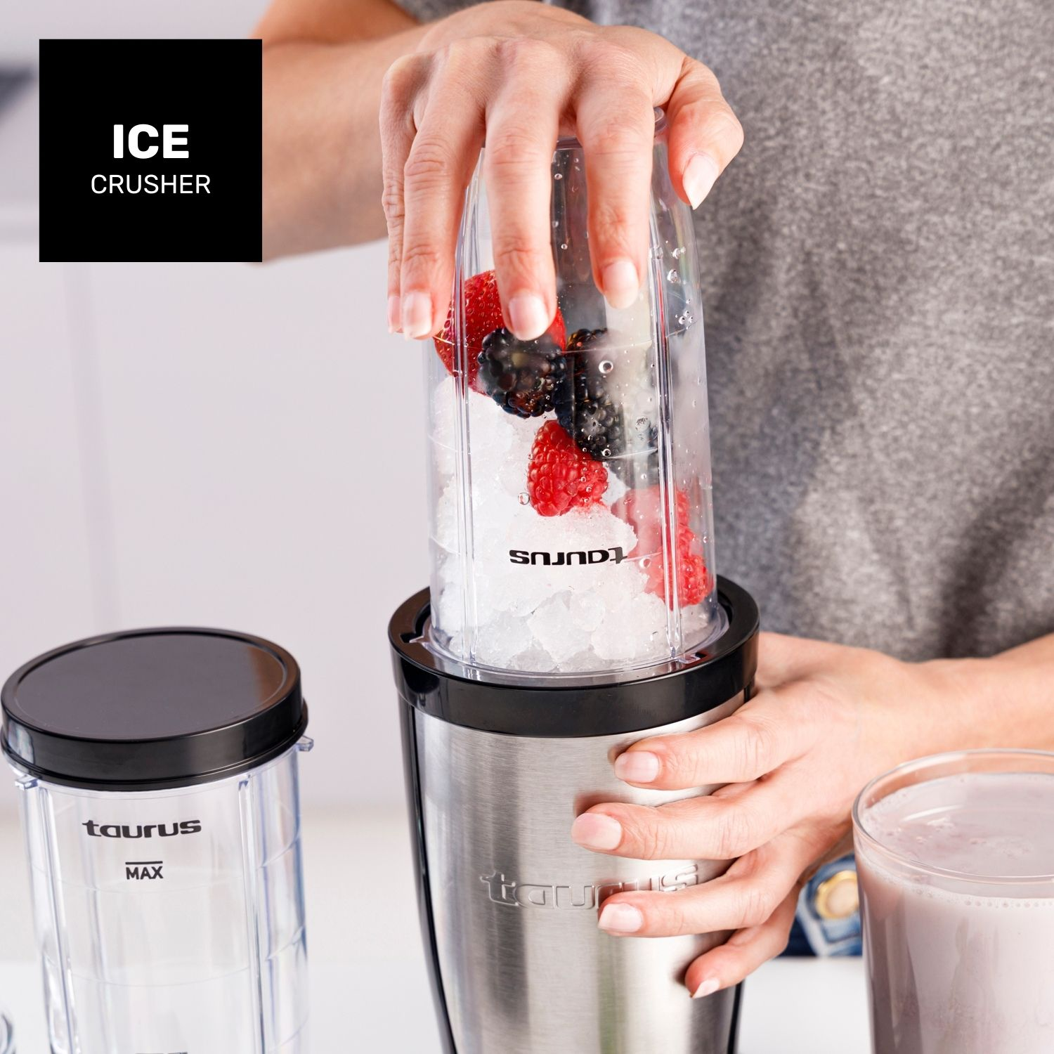 Una persona agrega bayas y hielo a un vaso de licuadora.