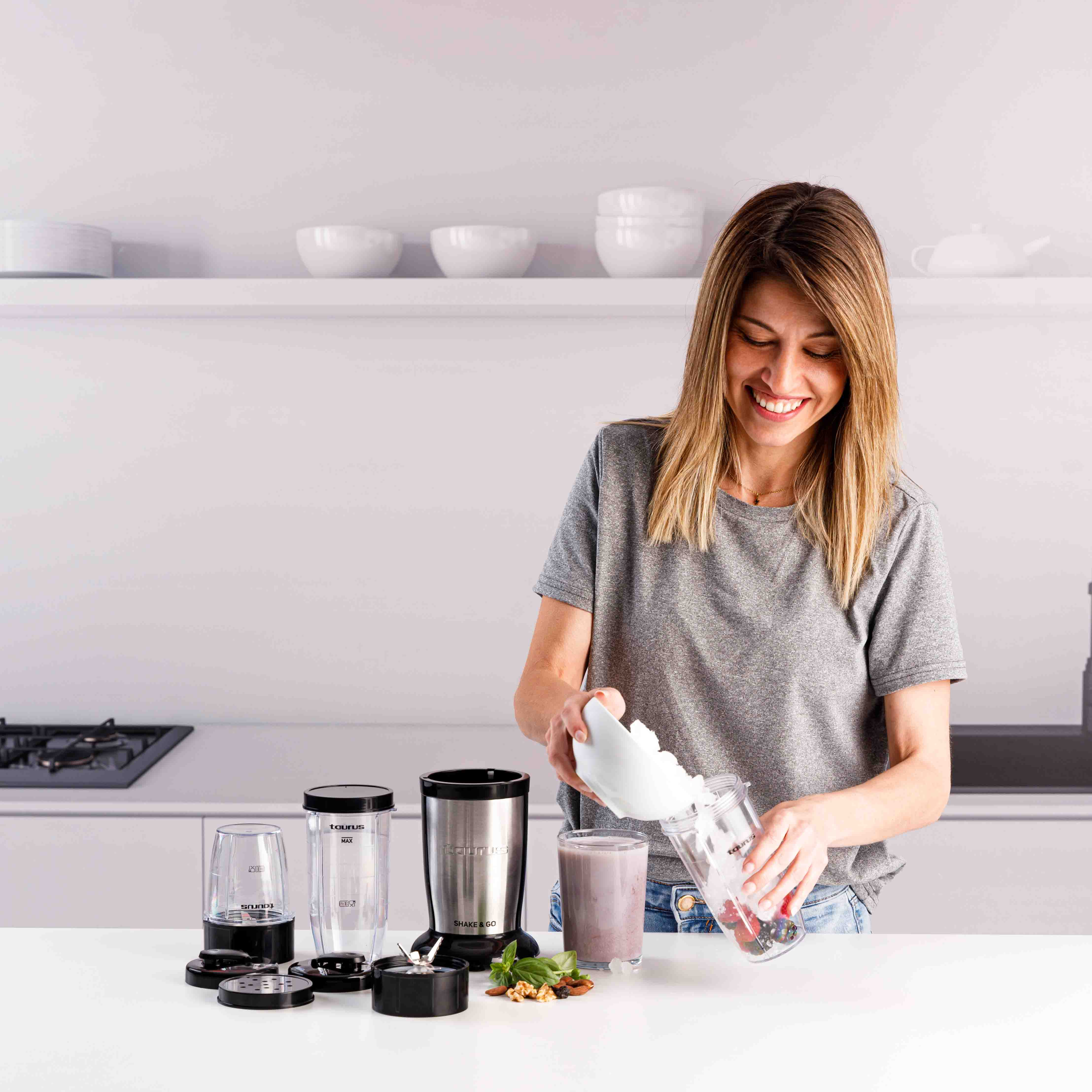 Una mujer añade hielo a una batidora. Hay ingredientes al lado.