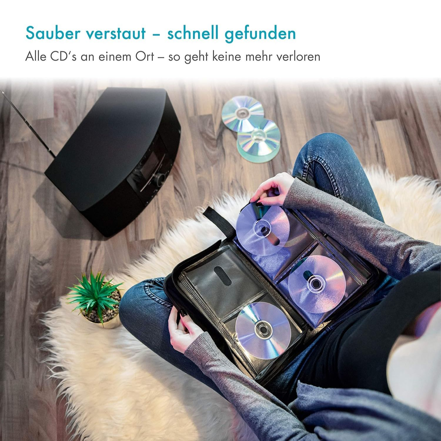 Person sortiert CDs in einer Hülle neben einem schwarzen CD-Player.