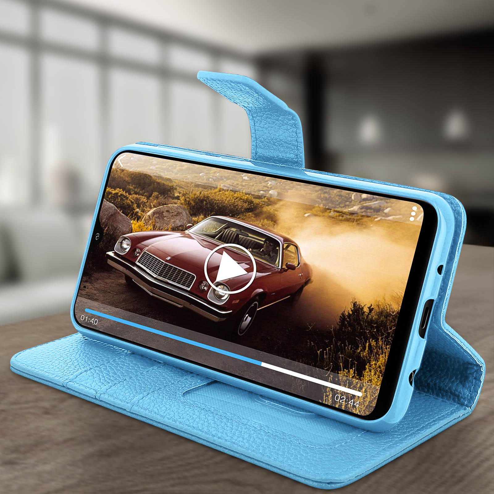 Telefoon in blauwe hoes toont video van rode auto die stof opwerpt.