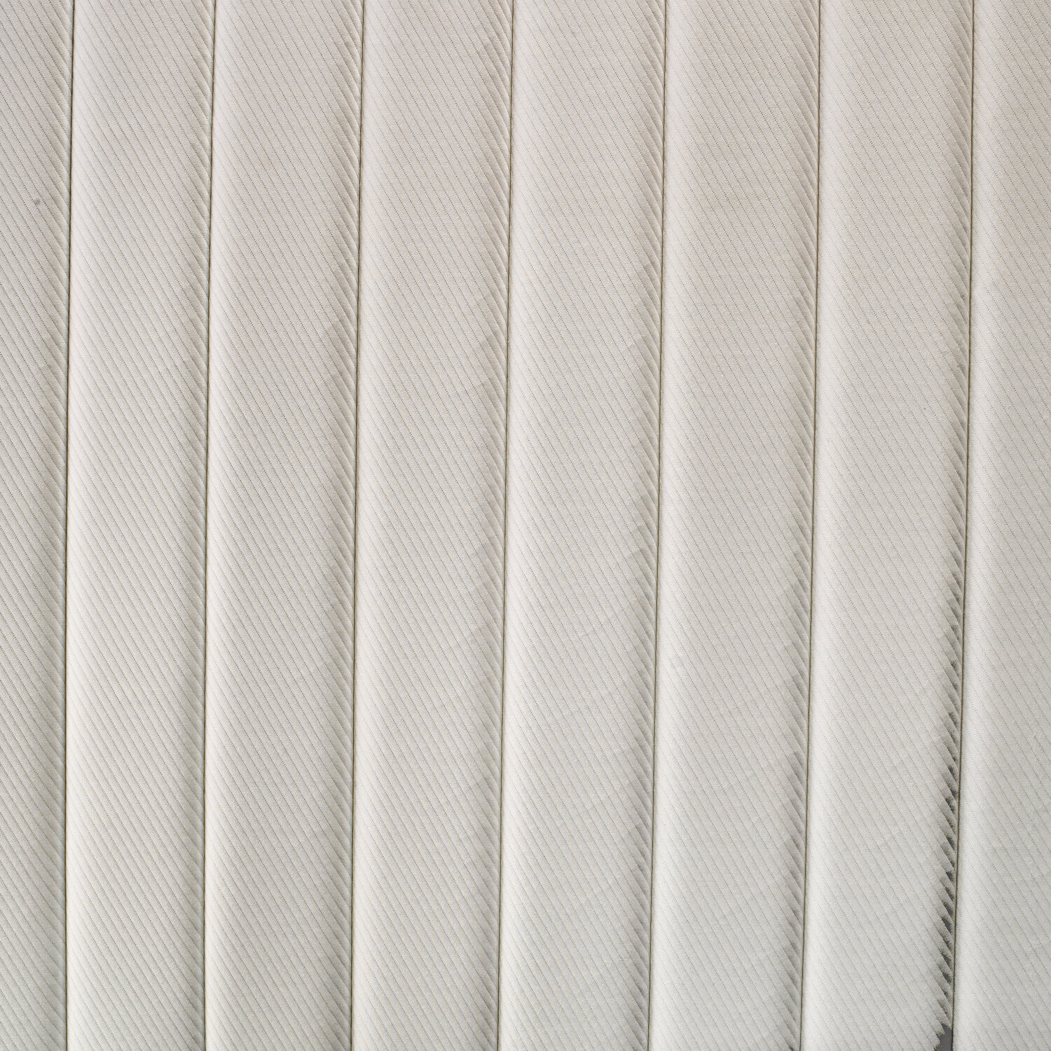 Un primer plano de una superficie acolchada beige claro con pliegues verticales.