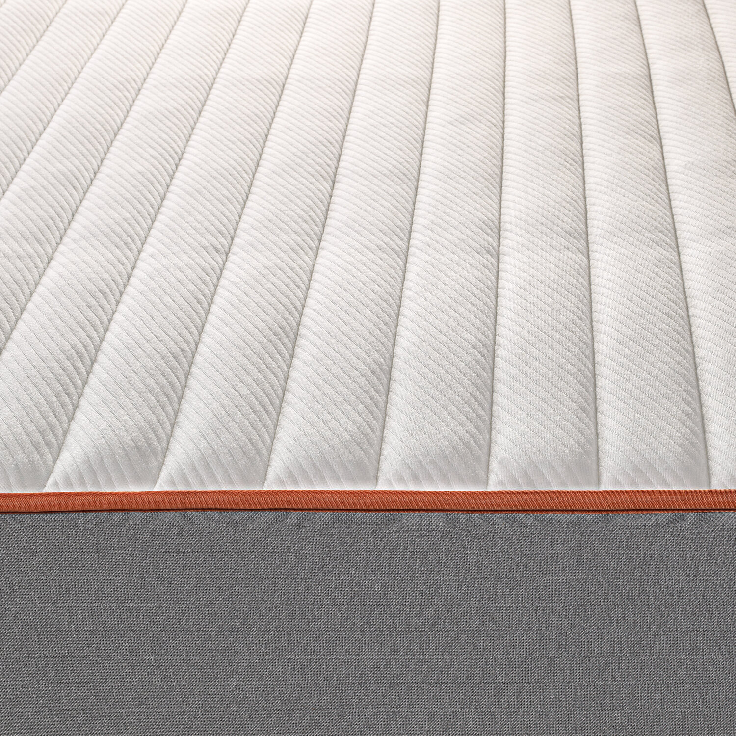 Colchón blanco acolchado con borde naranja y base de tela gris.