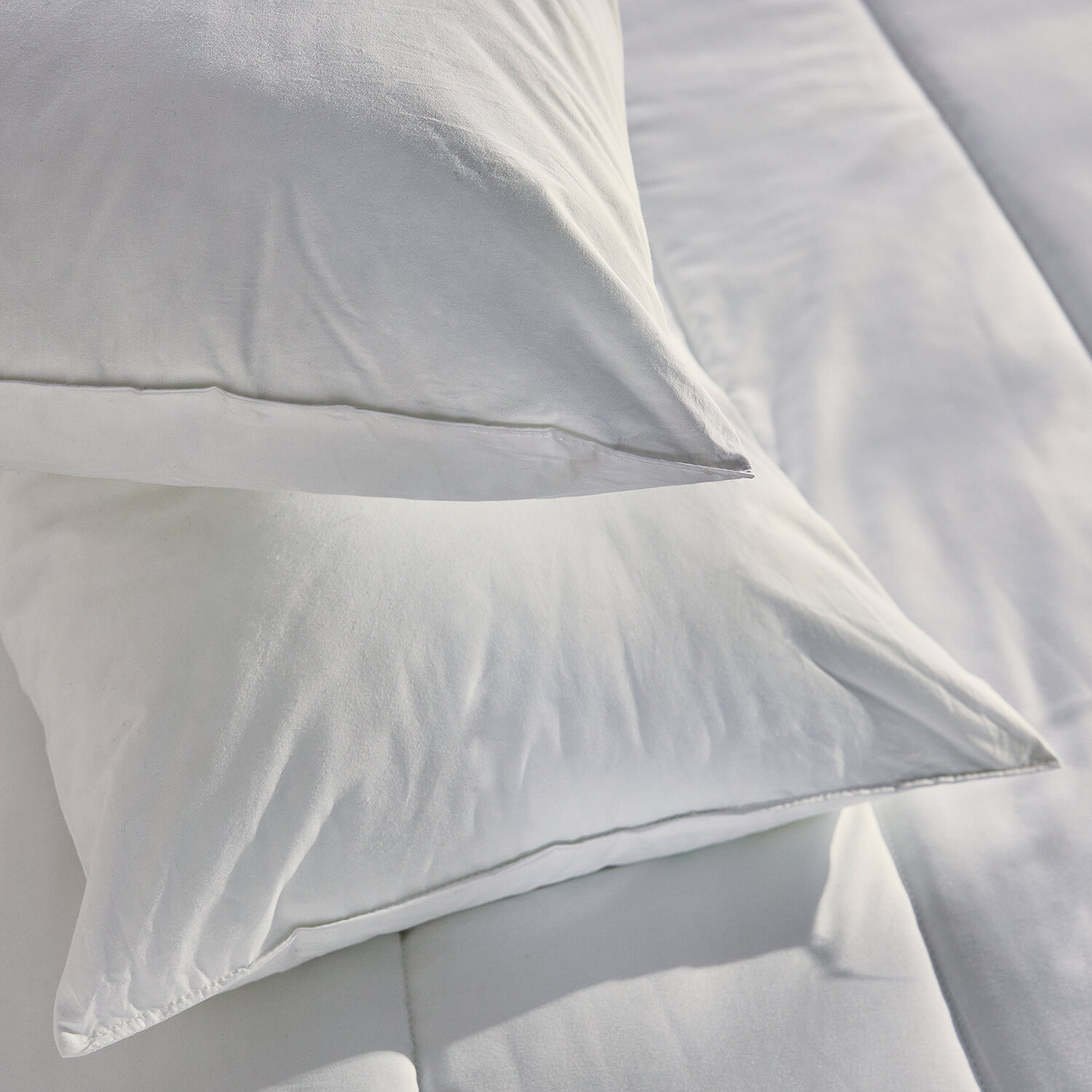 Dos almohadas blancas apiladas una encima de la otra en una cama.