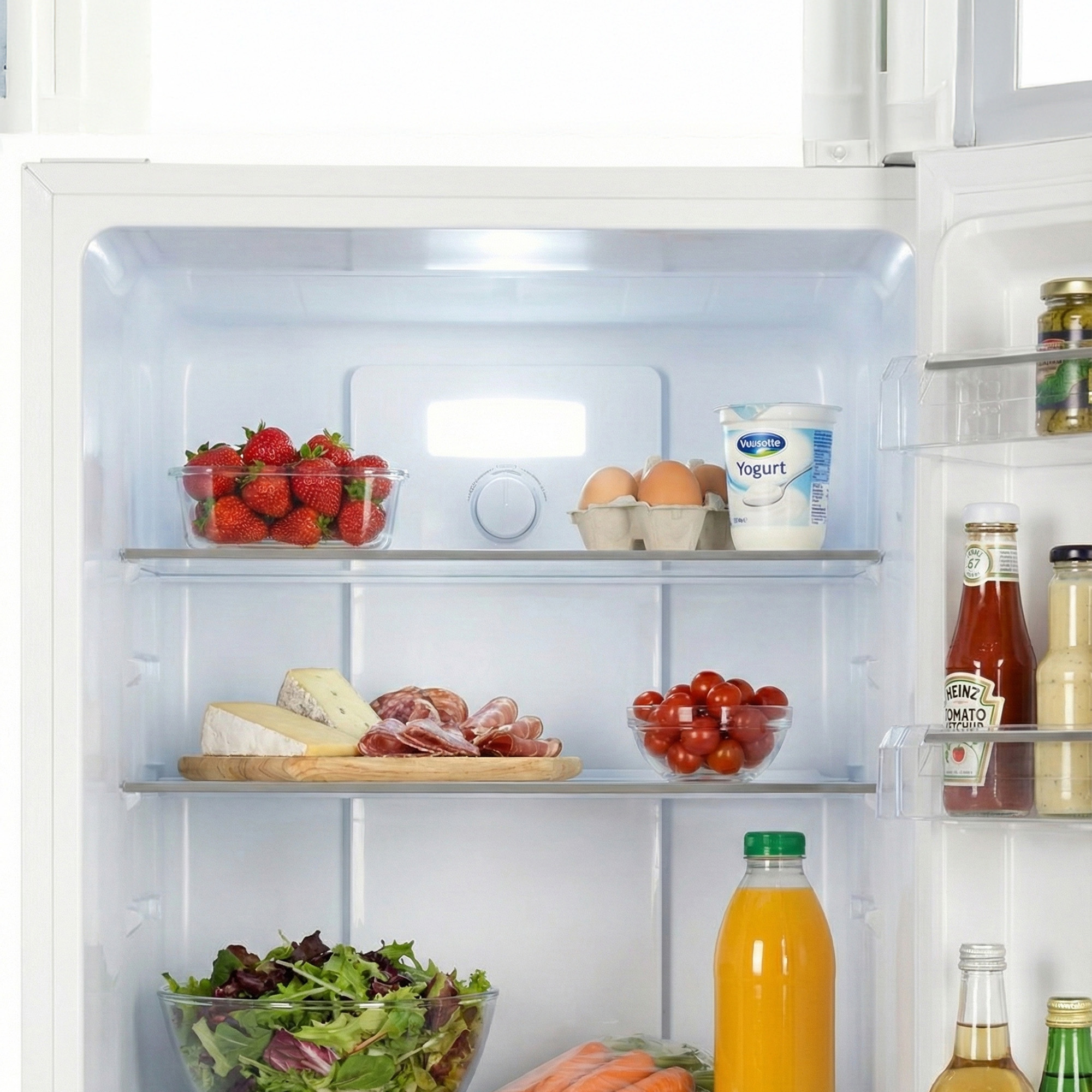 Volle koelkast met aardbeien, eieren, yoghurt, vleeswaren, kaas, salade en dranken.