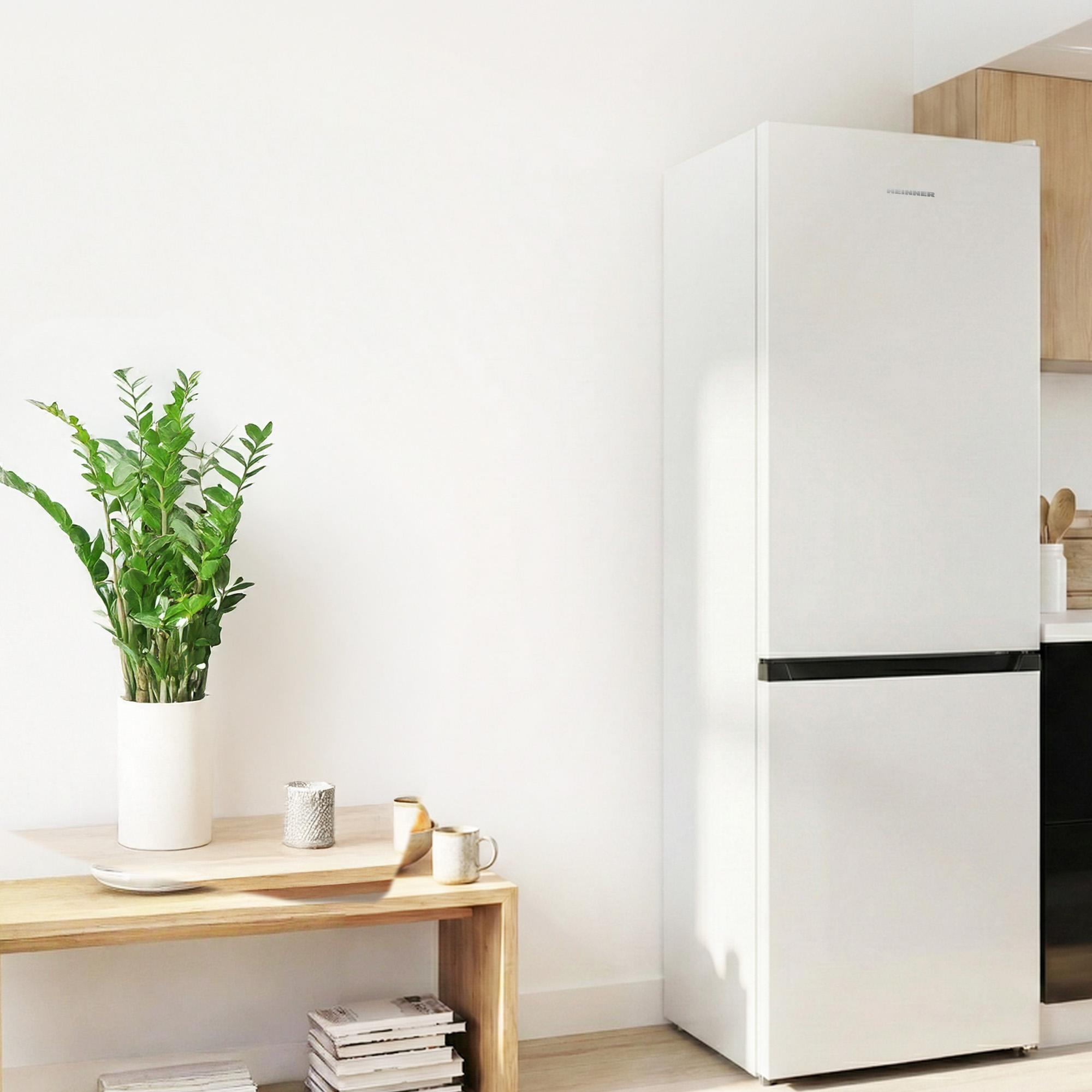Een witte koelkast naast een houten tafel met planten en kopjes.