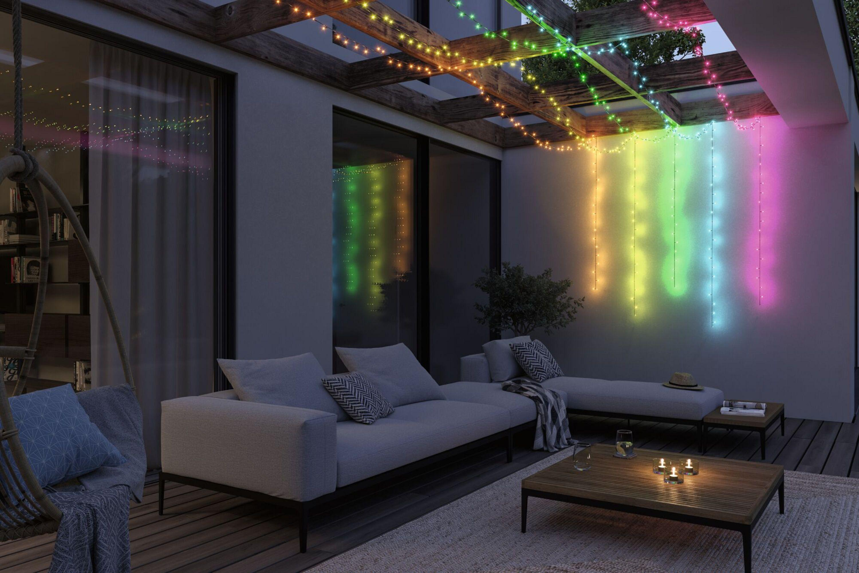 Zadaszony taras z meblami i kolorowymi lampkami nocą.
