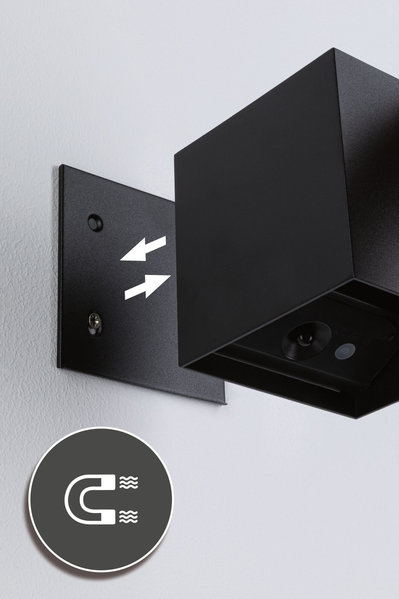 Czarny sześcian z mocowaniem magnetycznym na białej ścianie.