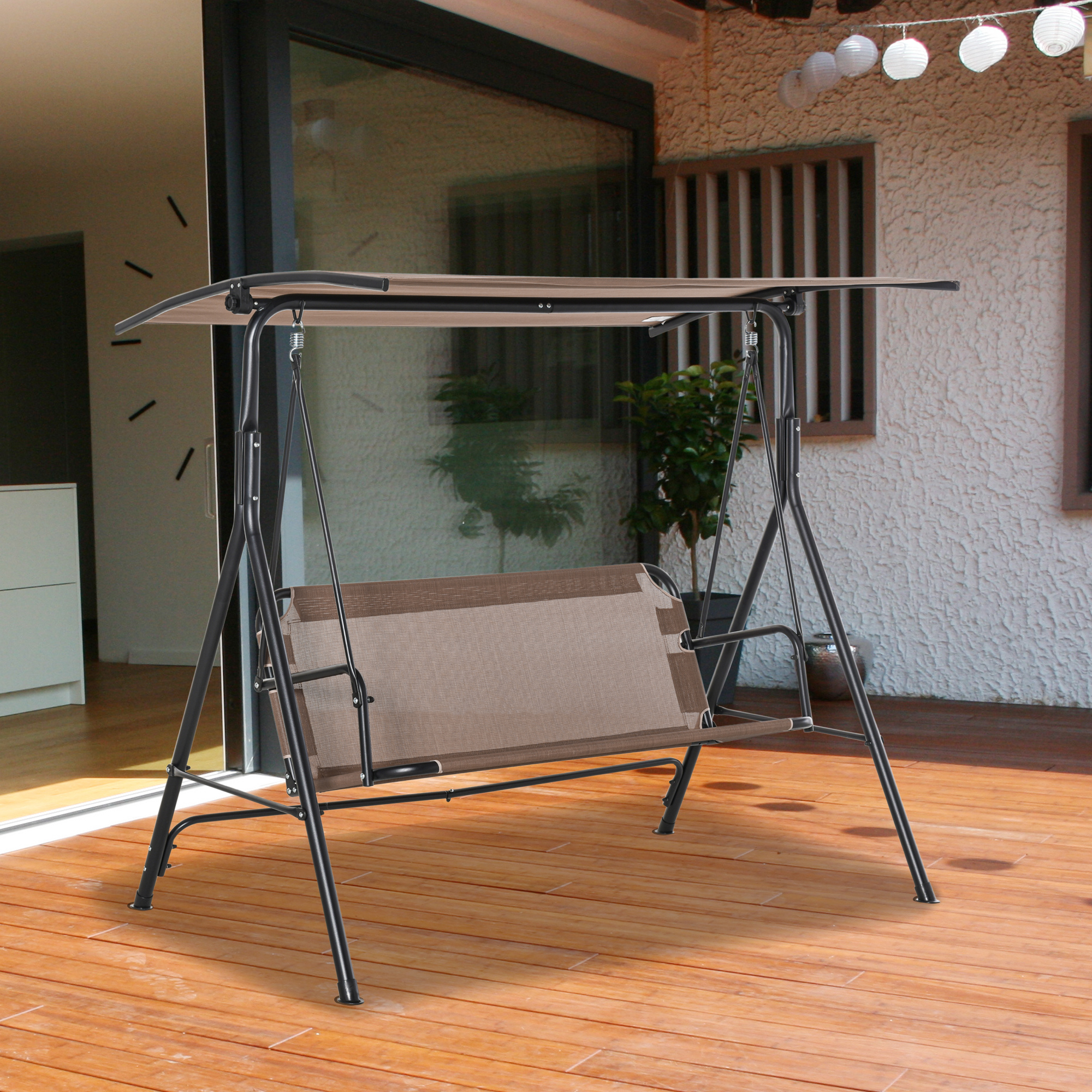 Un columpio marrón con marco negro descansa sobre una terraza de madera.