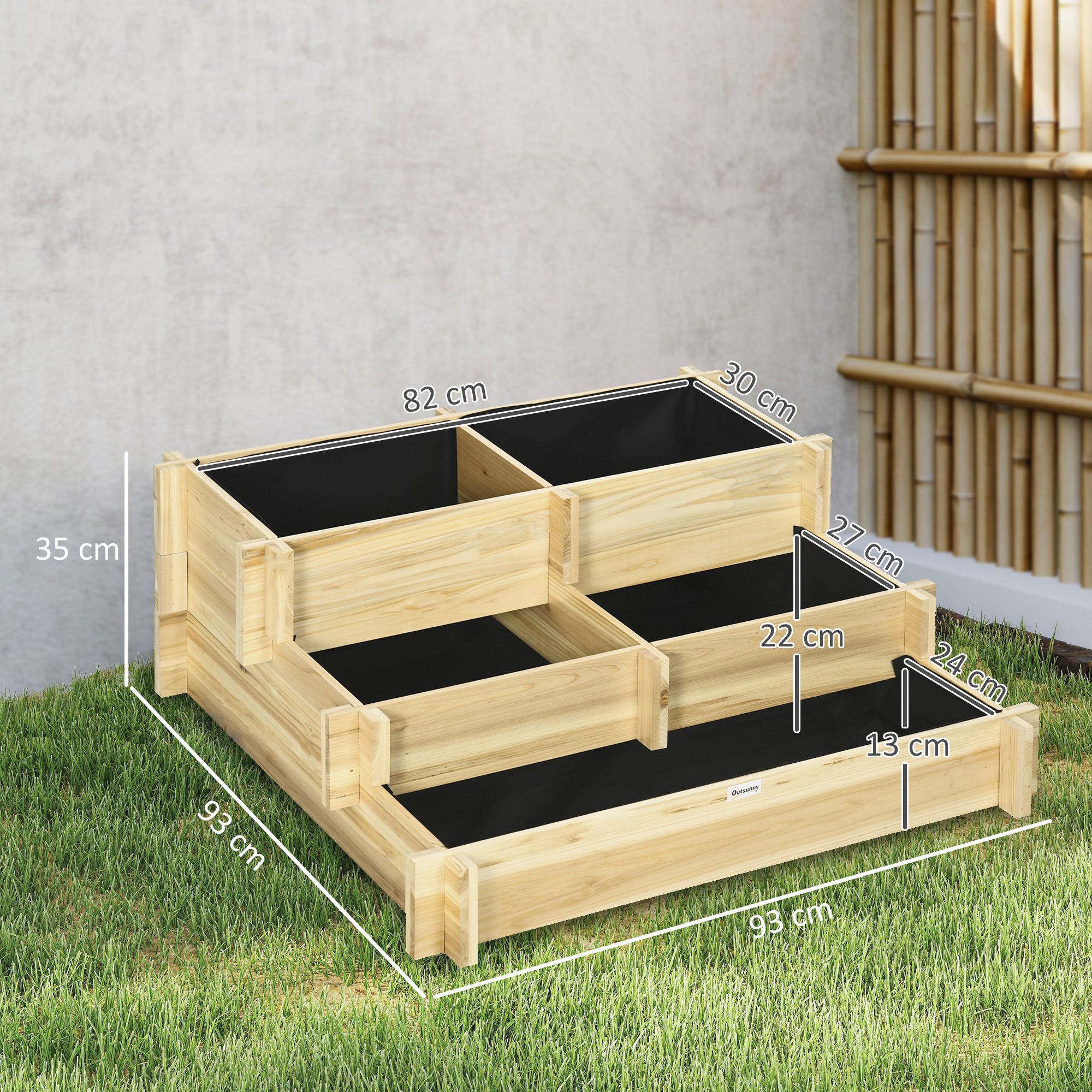 Un bancal elevado de madera escalonado con revestimientos negros sobre césped.