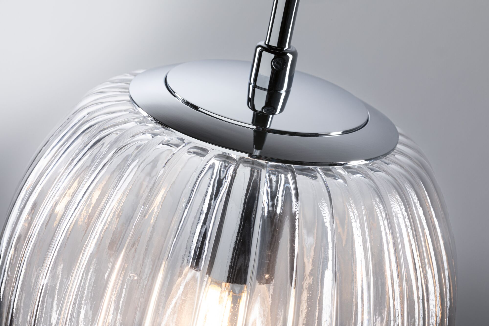 Ein detaillierter Blick auf eine geriffelte Glaslampe mit Chromdetails.